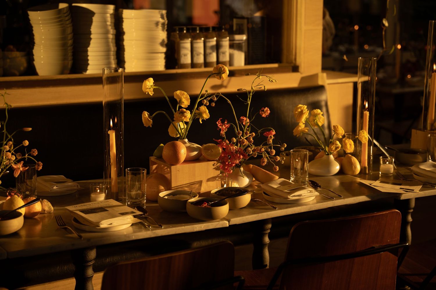 A dimly lit restaurant interior with tables and shelving visible.