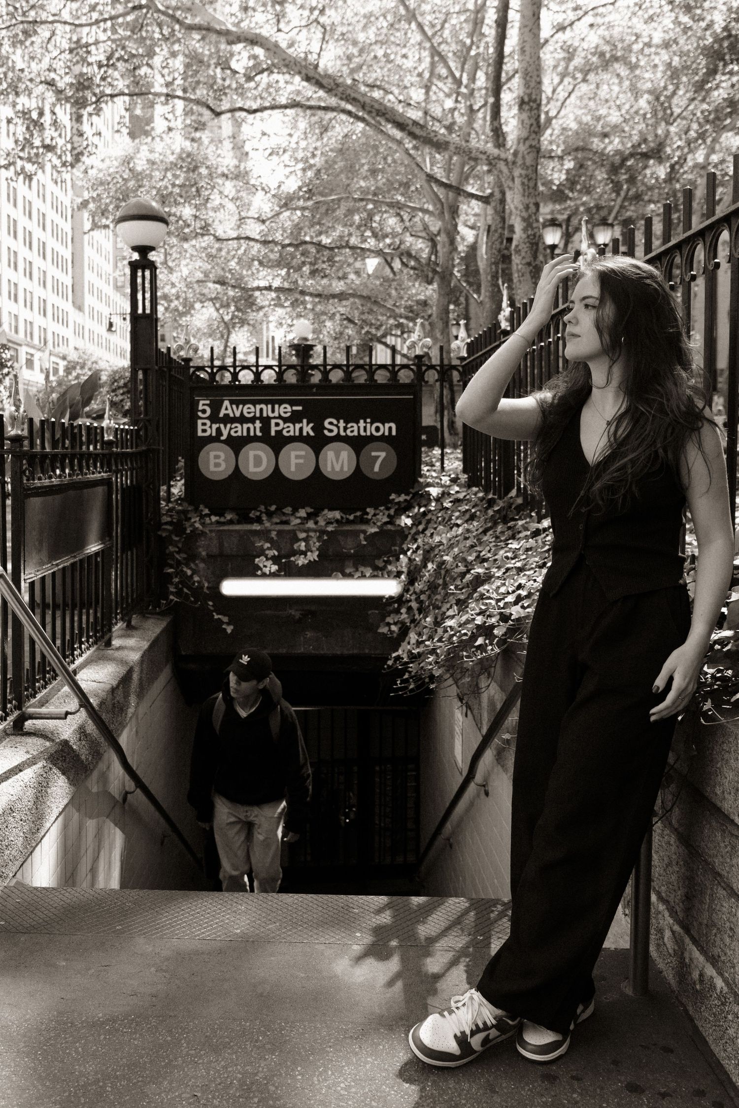 Black and white photos of a person in casual wear near Bryant Park Station entrance.