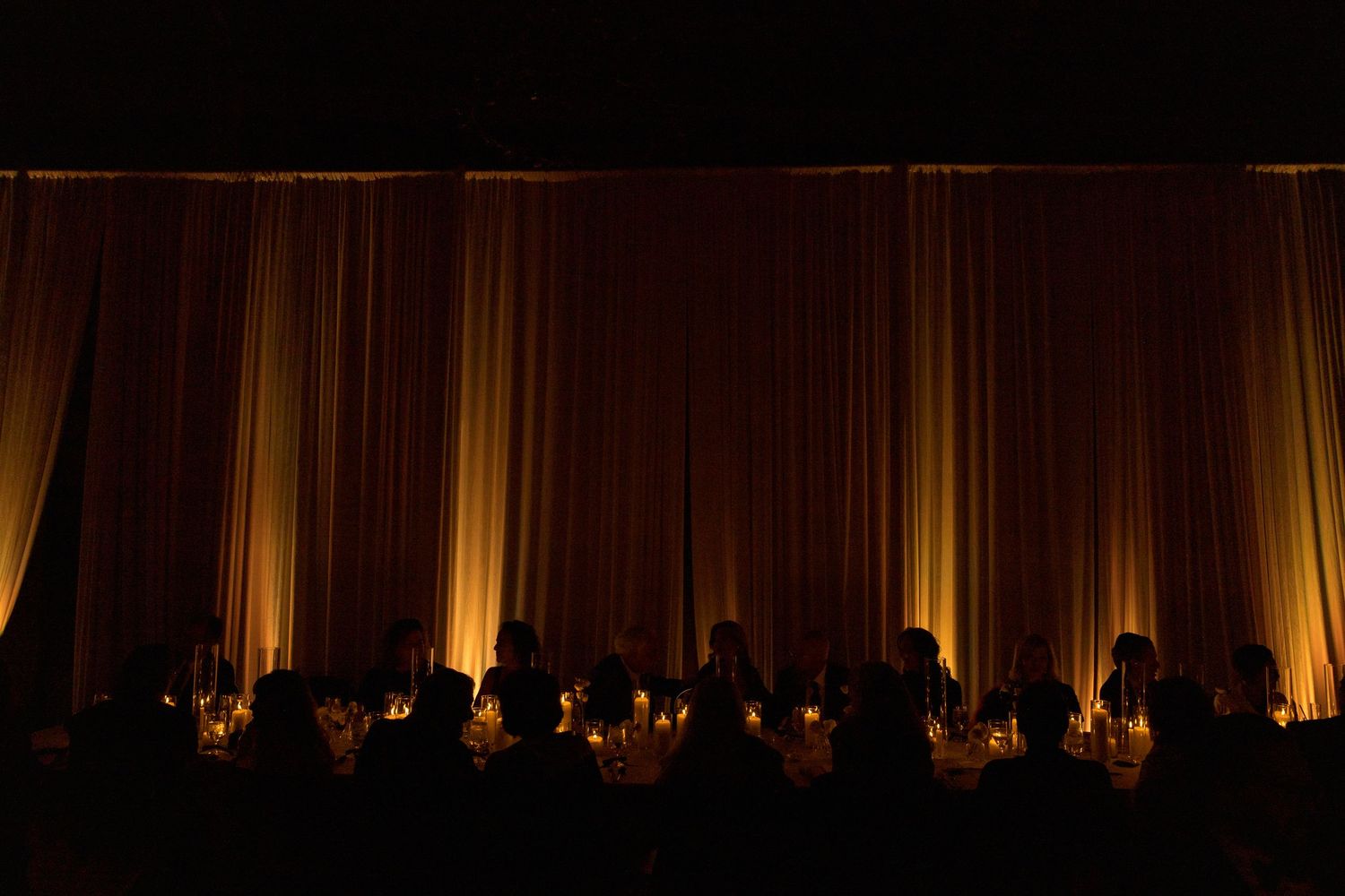 Dramatic amber uplighting illuminates elegant draped fabric at evening event.
