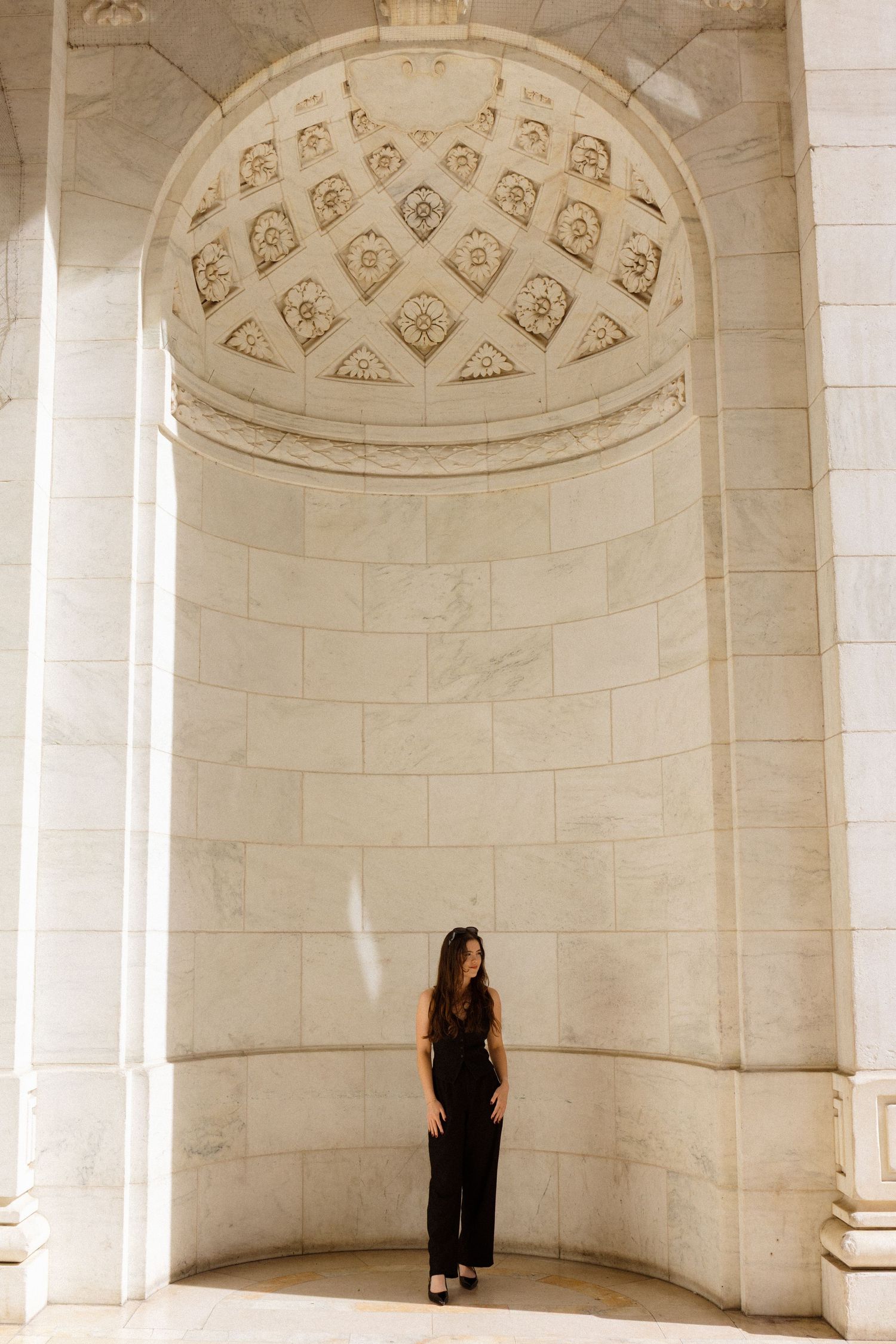 Person standing in ornate white marble alcove with decorative domed ceiling.