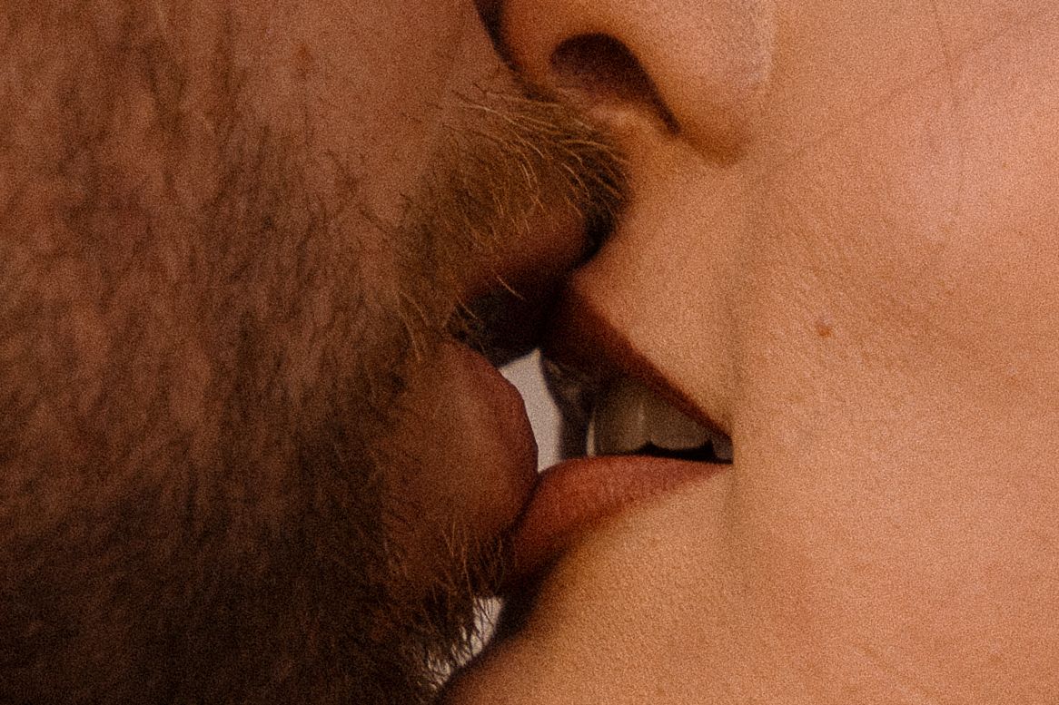 Close-up artistic shot of two people sharing an intimate kiss.