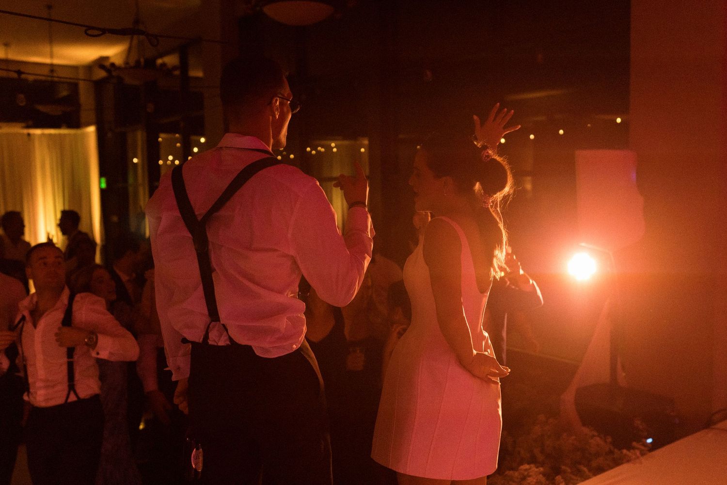 Silhouettes of party guests dancing in warm red lighting.
