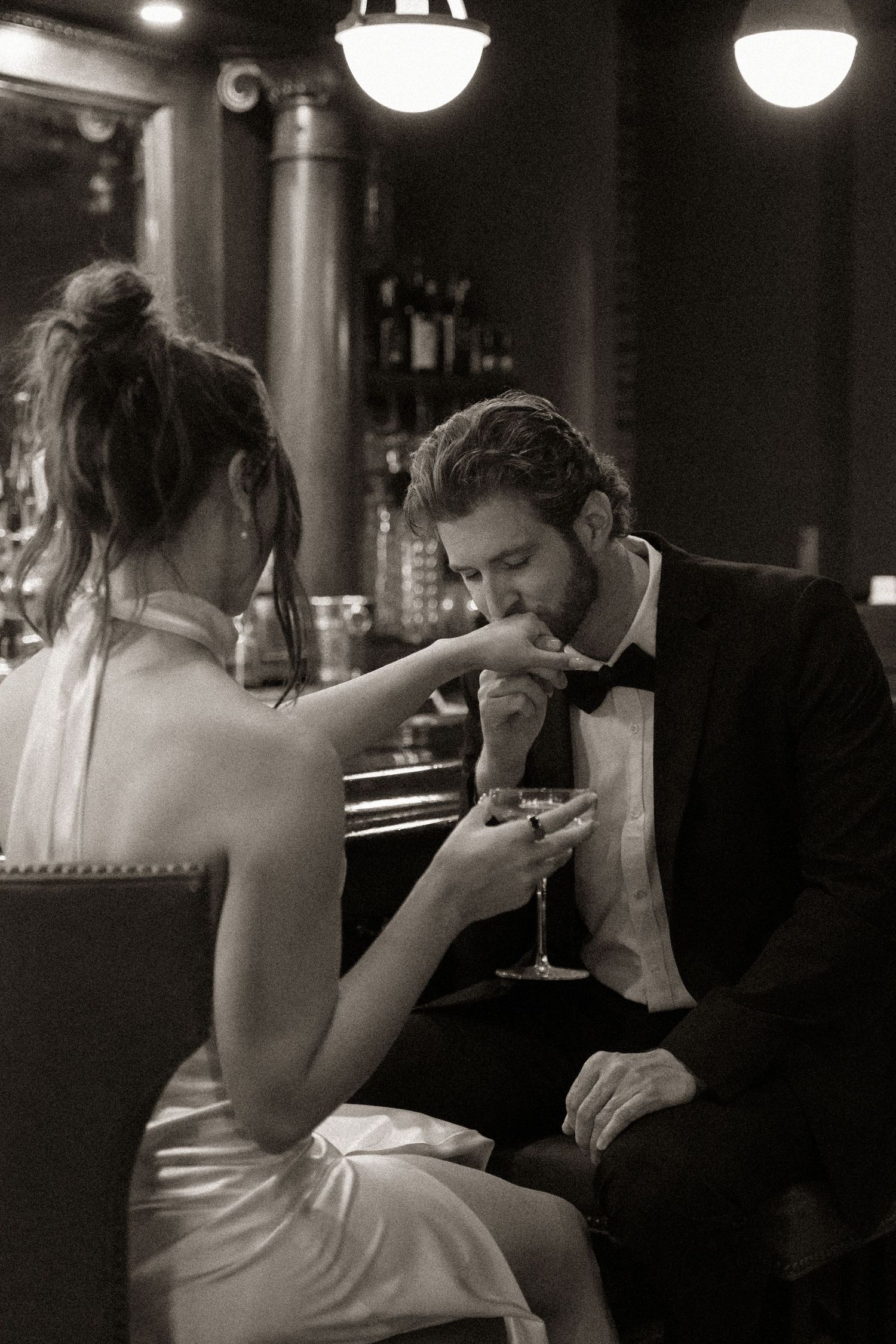 Black and white photo of a couple sharing an intimate moment at a bar.