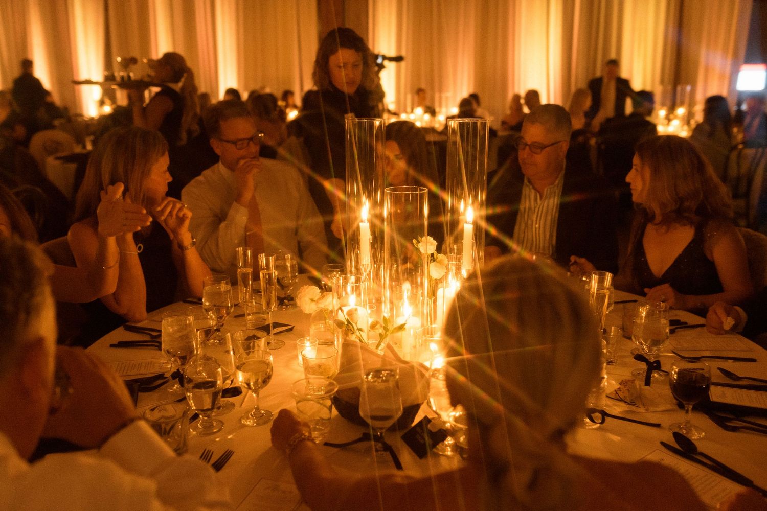 Warm candlelit tables create an elegant ambiance at an evening reception.