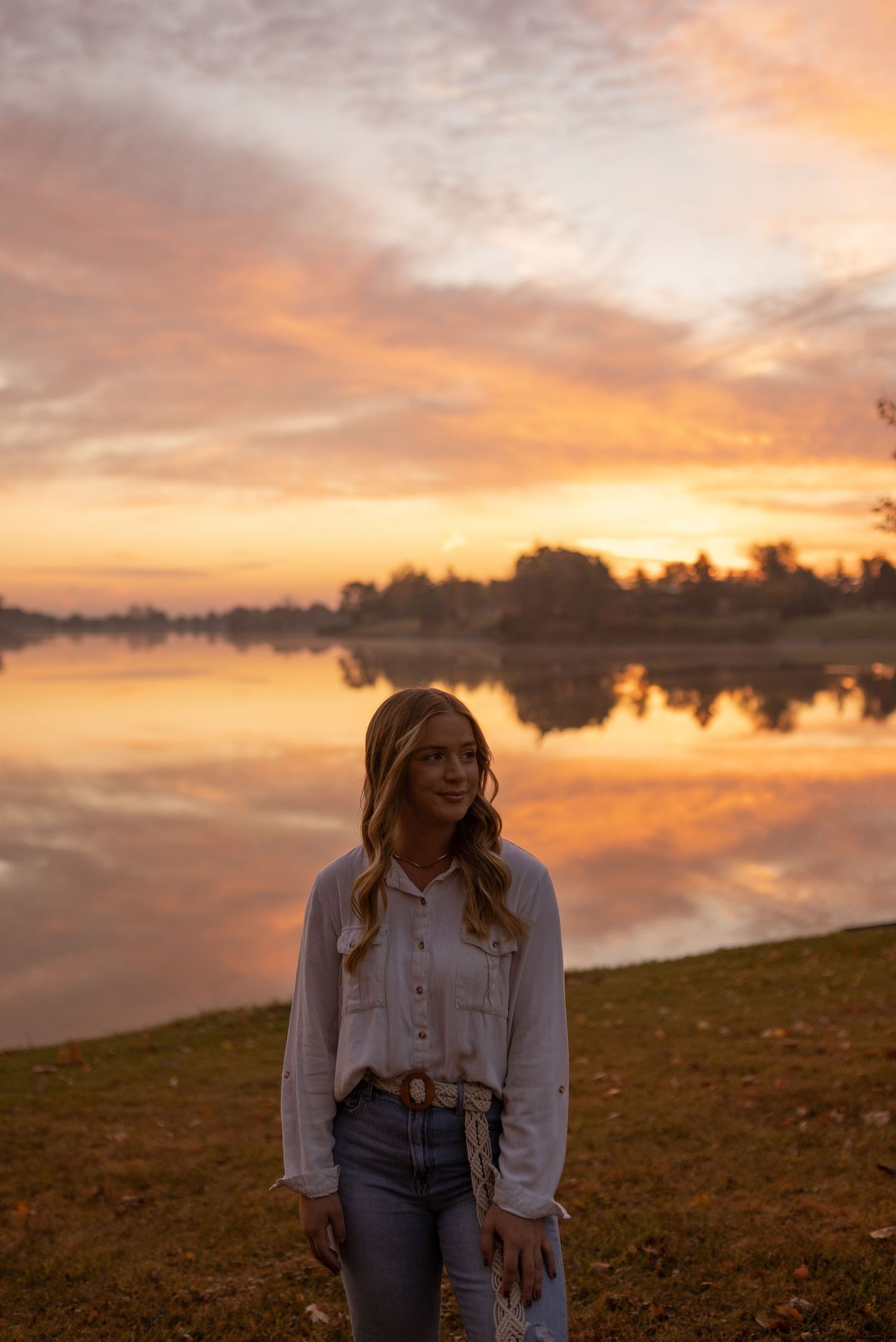 Sunset portrait session by a lake with golden hour lighting and reflective waters.