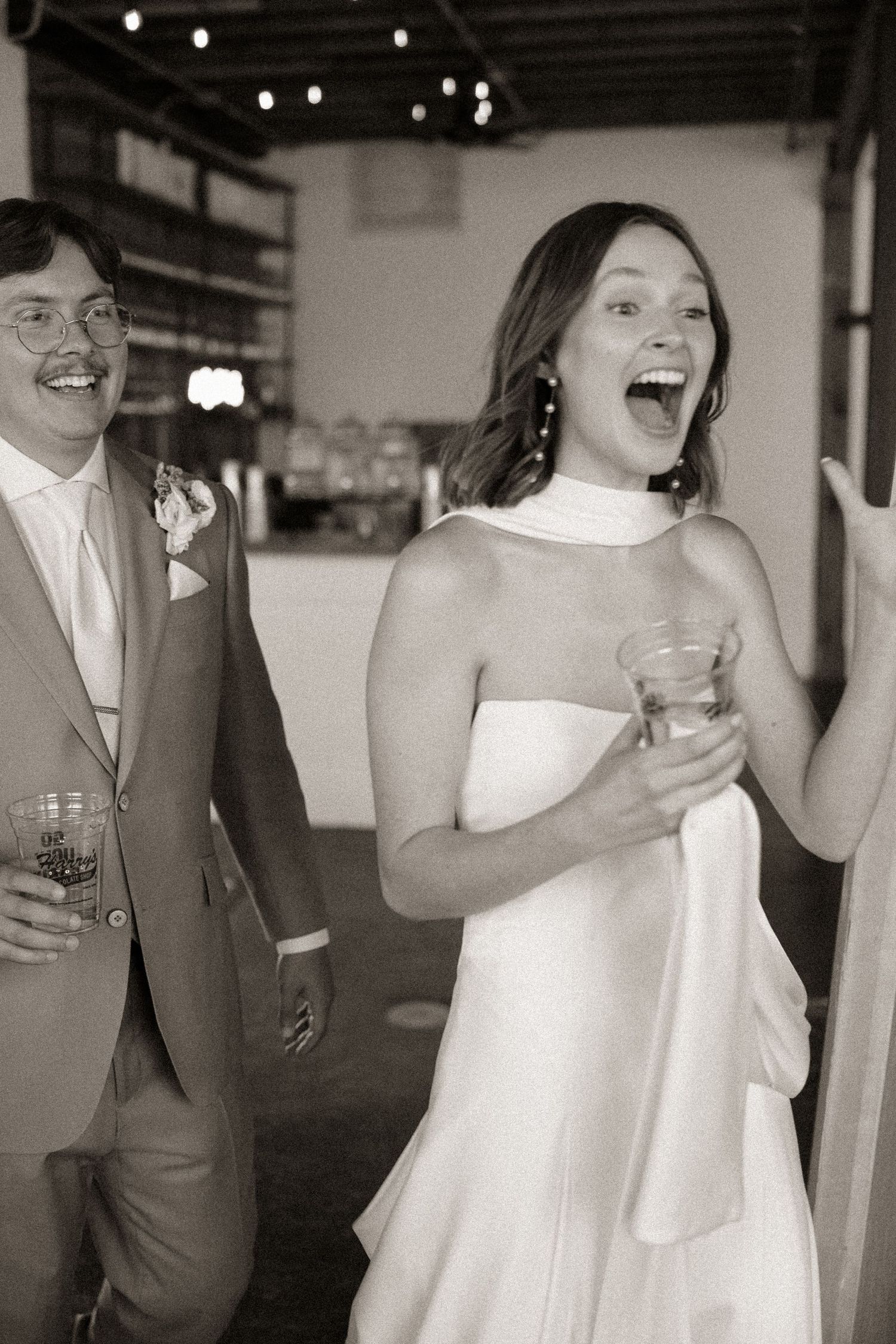 Wedding celebration candid moments with couple laughing and holding drinks.
