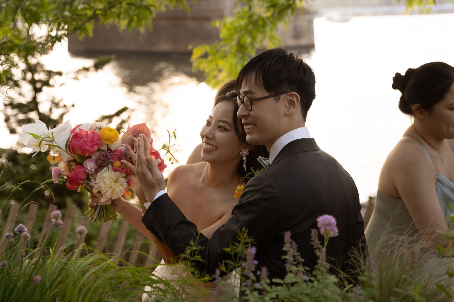 Wedding guests gathered outdoors with colorful flowers and natural lighting.