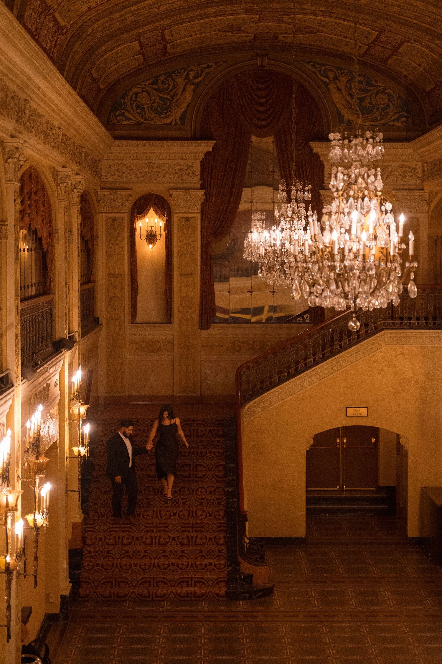 An elegant ballroom with crystal chandeliers and classical architecture captured in warm lighting.