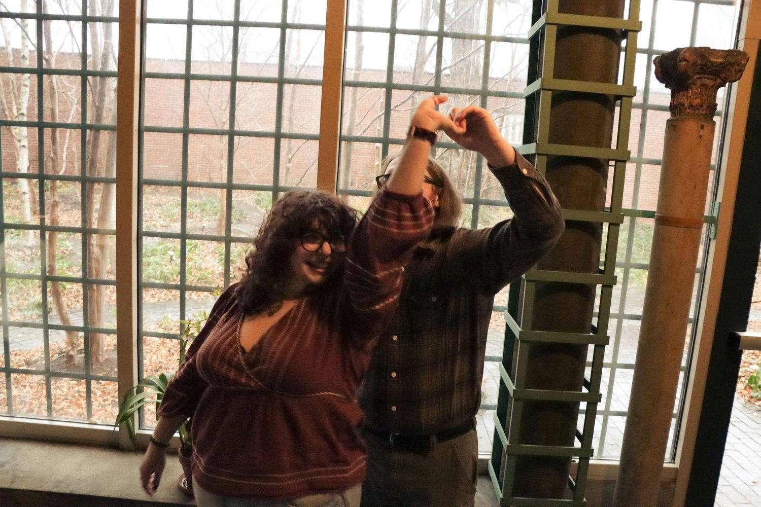 A cheerful couple dances together joyfully by a bright window.