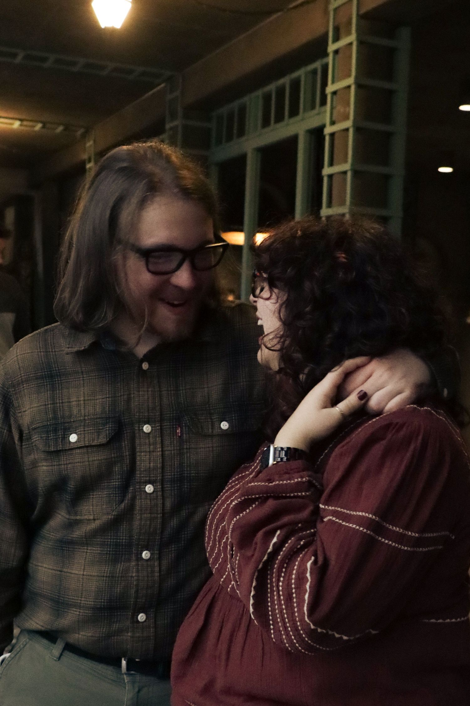 A couple looks at each other with loving eyes and smiles in a romantic embrace.