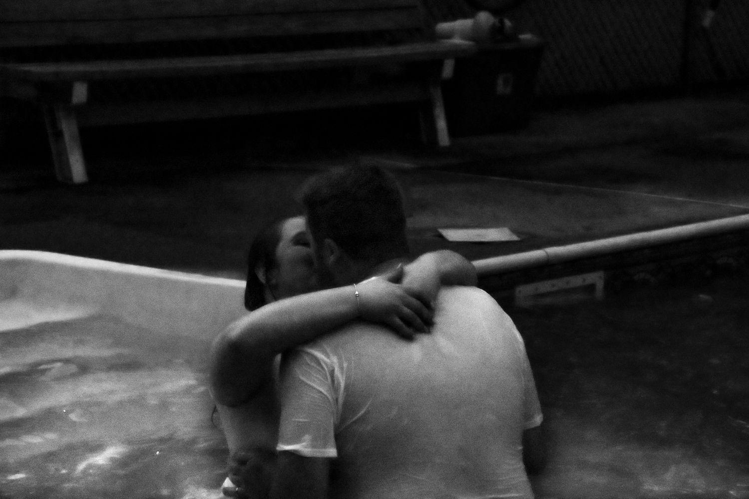 Black and white photo of a bride and groom sharing an intimate moment after jumping into a pool together.