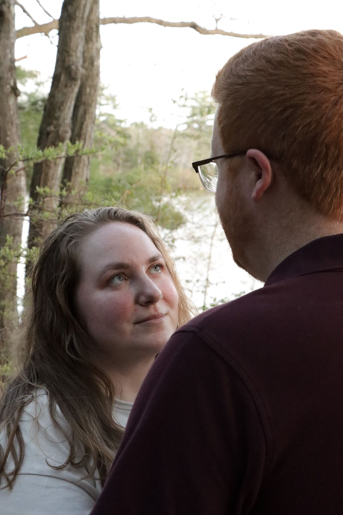 A romantic couple shares intimate moments in a series of outdoor portraits against a wooded backdrop.