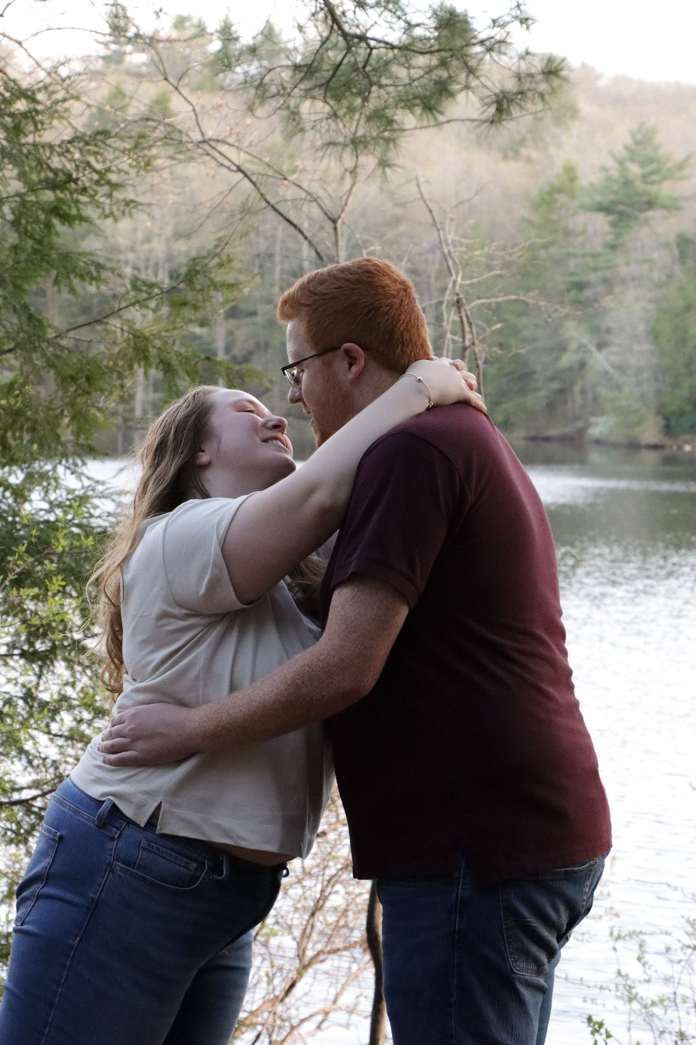 A happy couple shares a cheerful and romantic moment together with a beautiful lake background at a park.