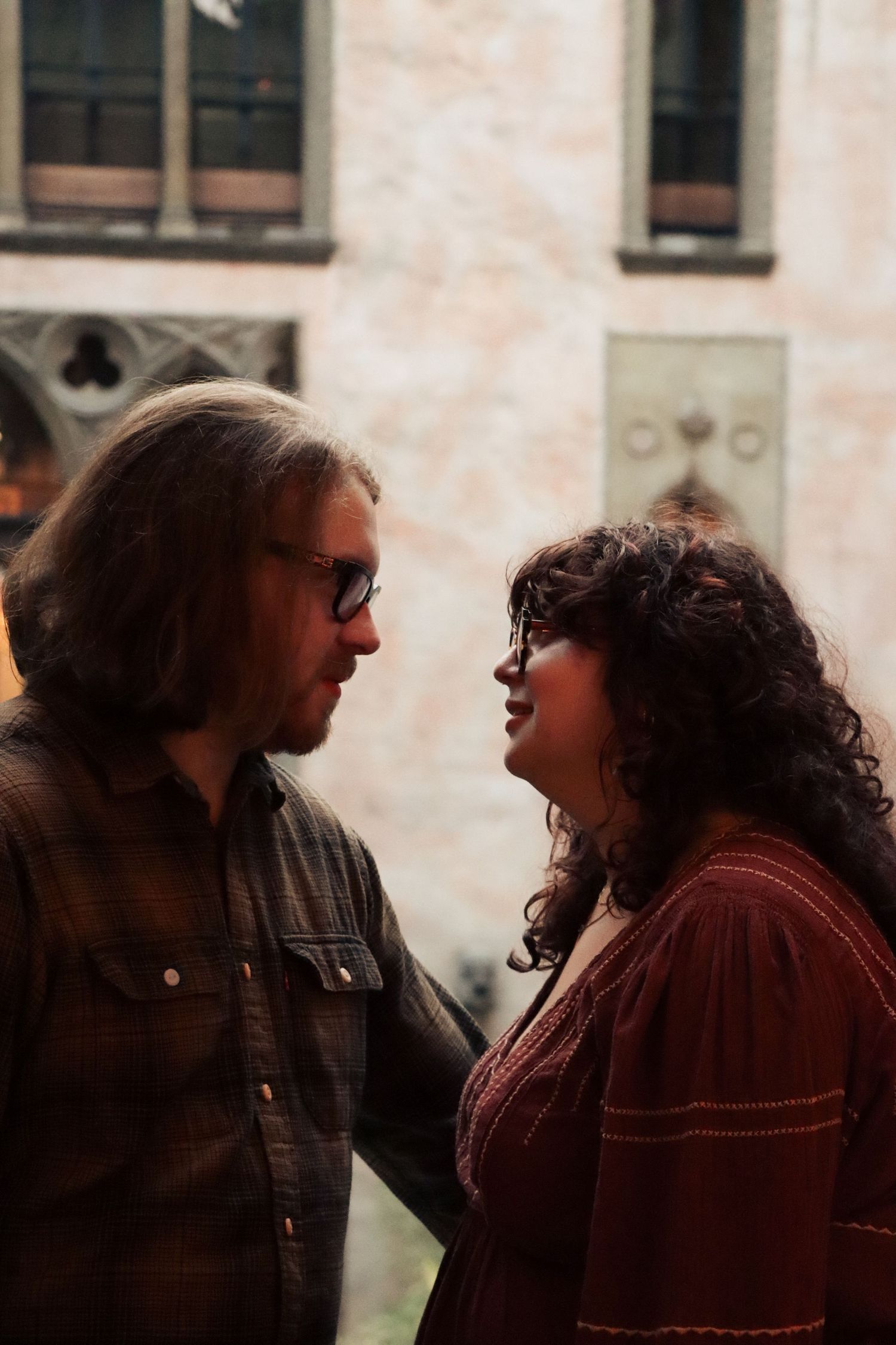 A couple looks lovingly into each others eyes in a warm and bright room of a Boston Massachusetts museum.