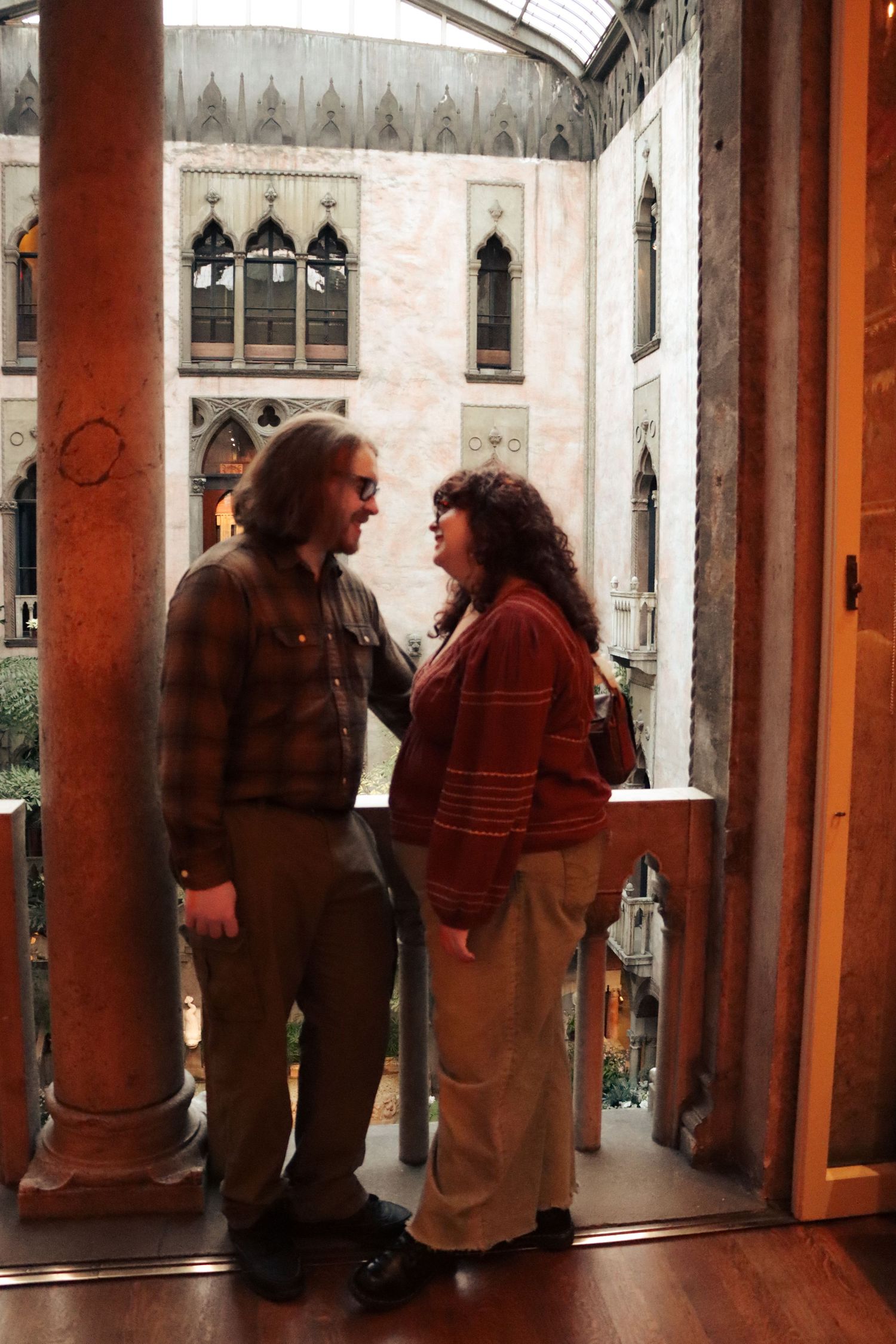 A couple looks lovingly into each others eyes in a warm and bright room of a Boston Massachusetts museum.