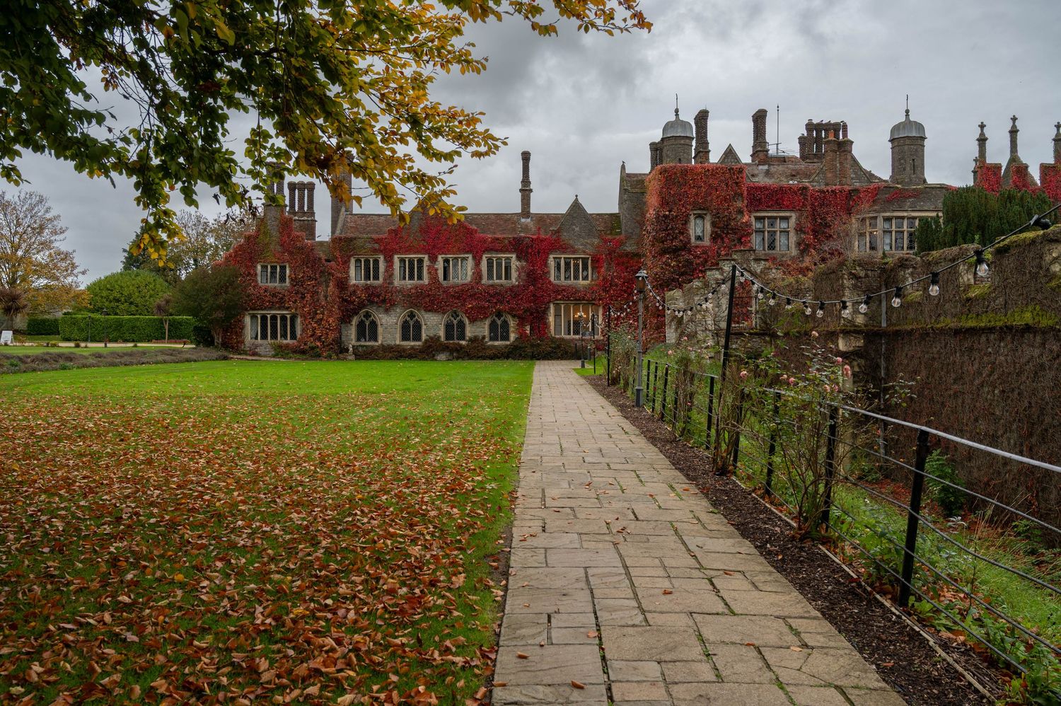 Moody autumnal scene with fallen leaves and country house