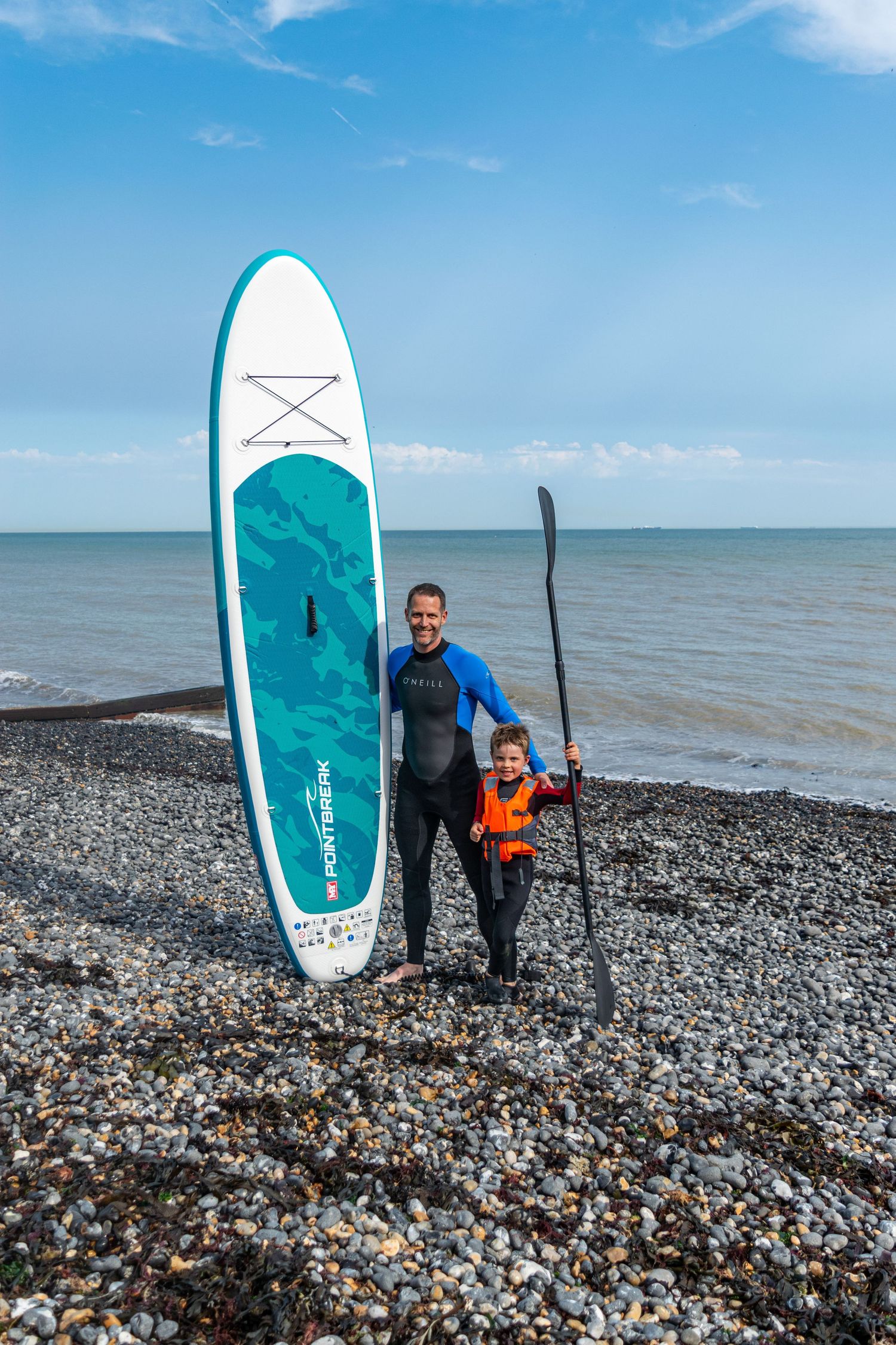 Father and son next to their sup at a beach, family photography Kent