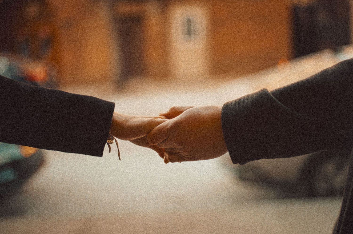 Two people shaking hands in a warm indoor setting with soft lighting and blurred background.