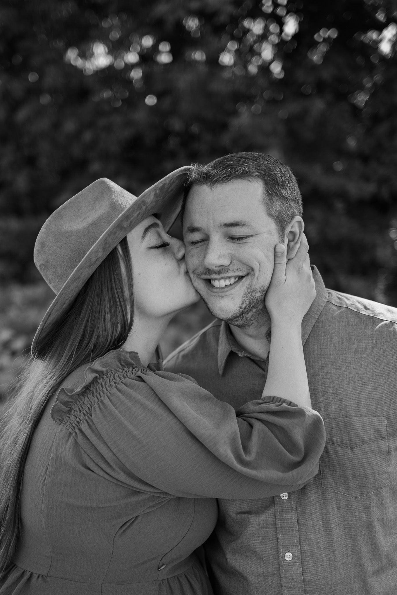 Black and white romantic portrait of a couple sharing an intimate moment outdoors.