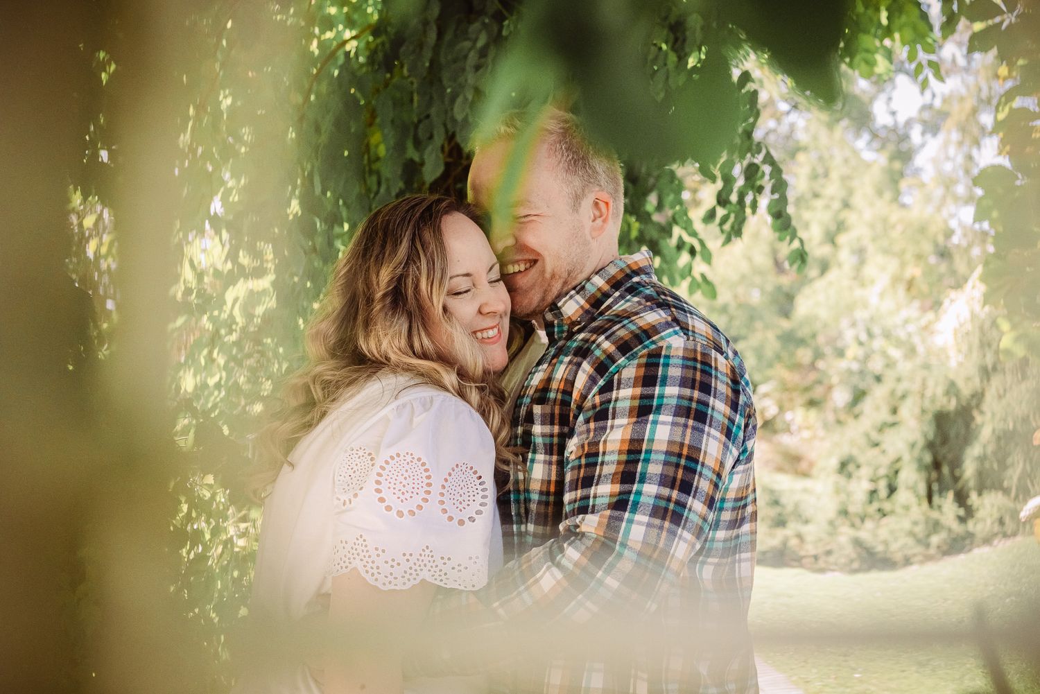 Romantic couple sharing intimate moment under blooming spring trees.