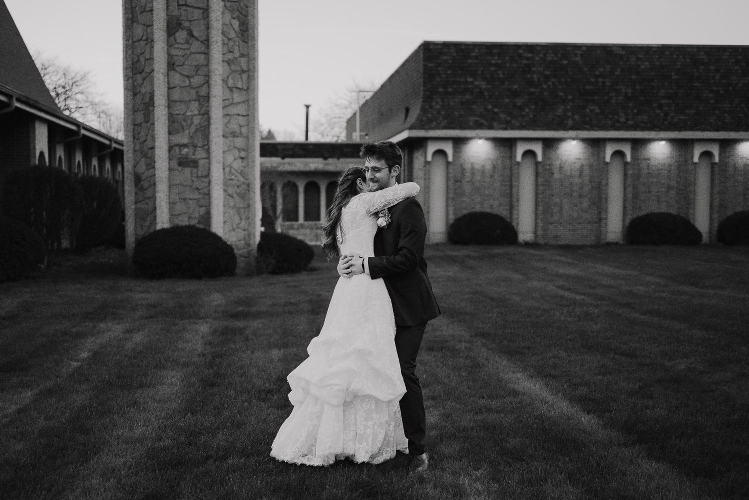 Wedding couple takes outdoor portraits against architectural backdrop at sunset.