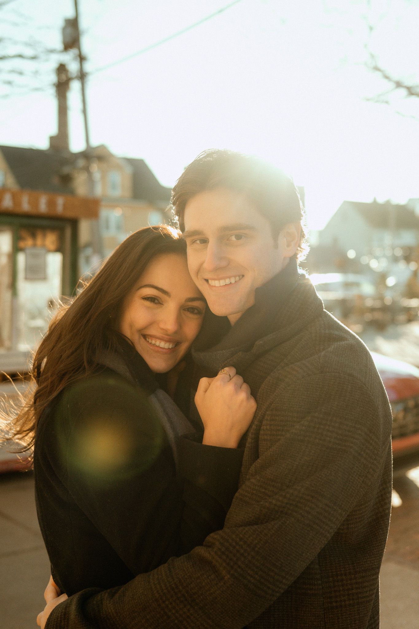 A couple shares a warm embrace outdoors during golden hour, creating a romantic and intimate moment.