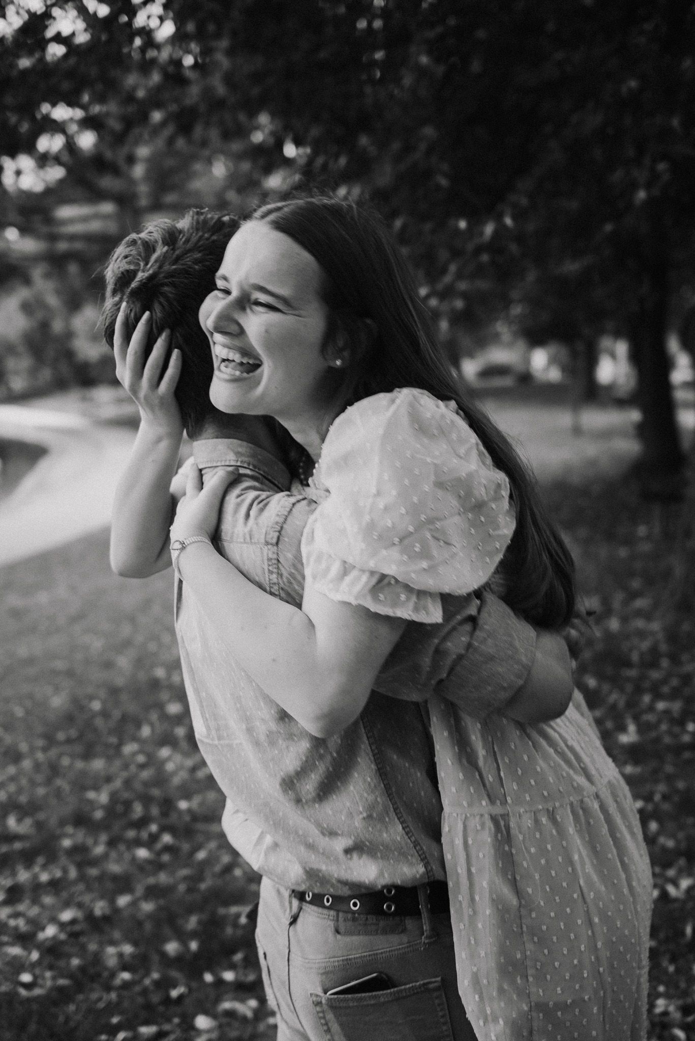 Two people sharing a joyful embrace and laughing together outdoors.