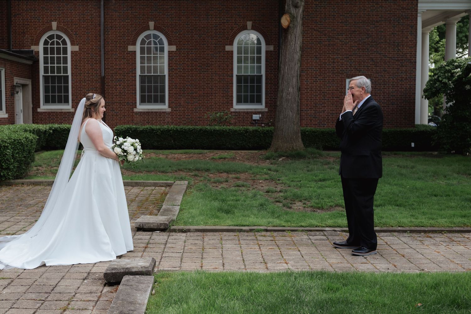 Wedding couple walks along brick pathway during outdoor photo session.