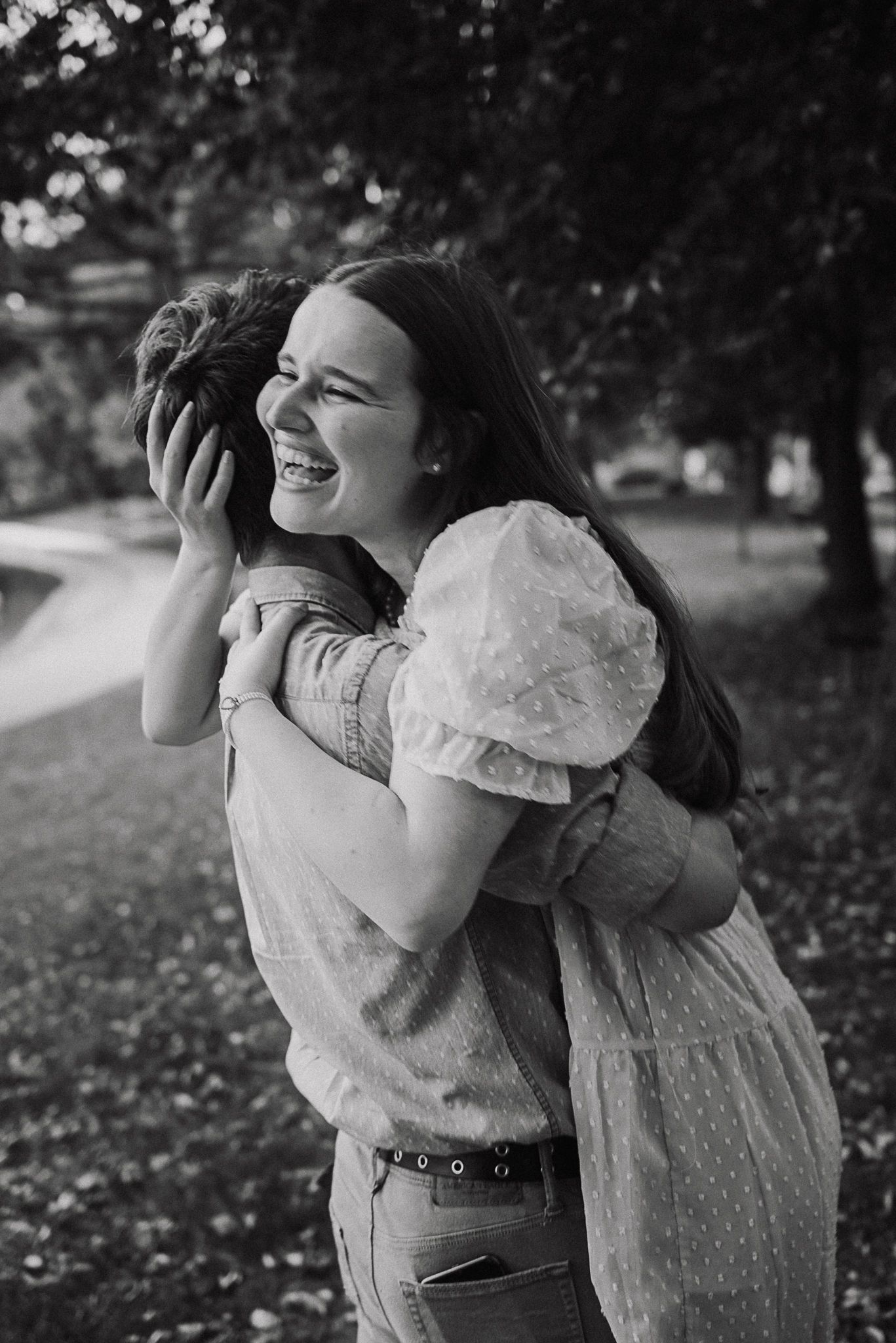 A series of black and white photos showing a joyful embrace between two people in a park setting.