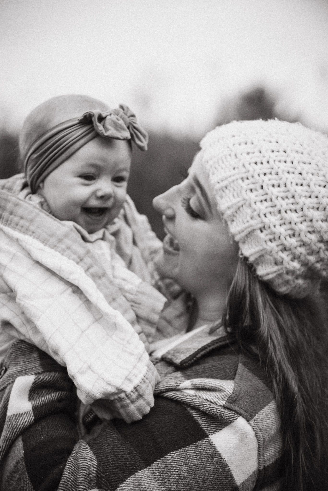 Intimate black and white moment between parent and baby wearing knit hat.