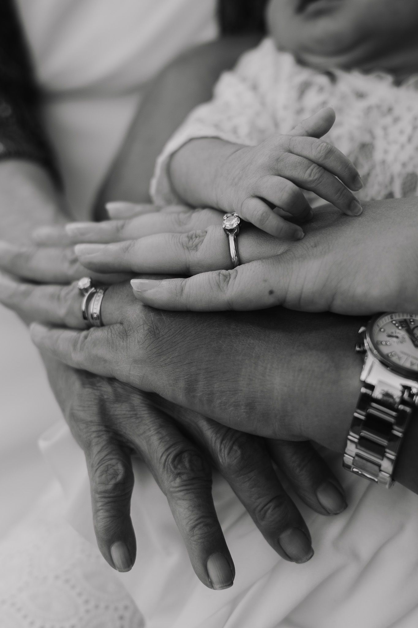 Multiple hands stack together showing wedding rings in black and white.