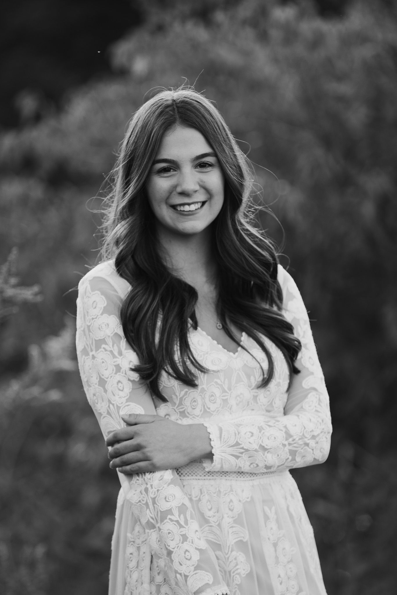 A romantic portrait in a lace dress against a blurred natural background.
