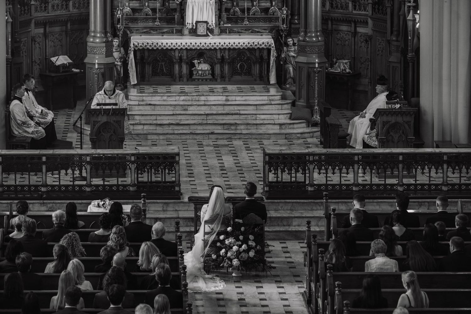 People sit in wooden church pews during a traditional religious service in a historic cathedral.