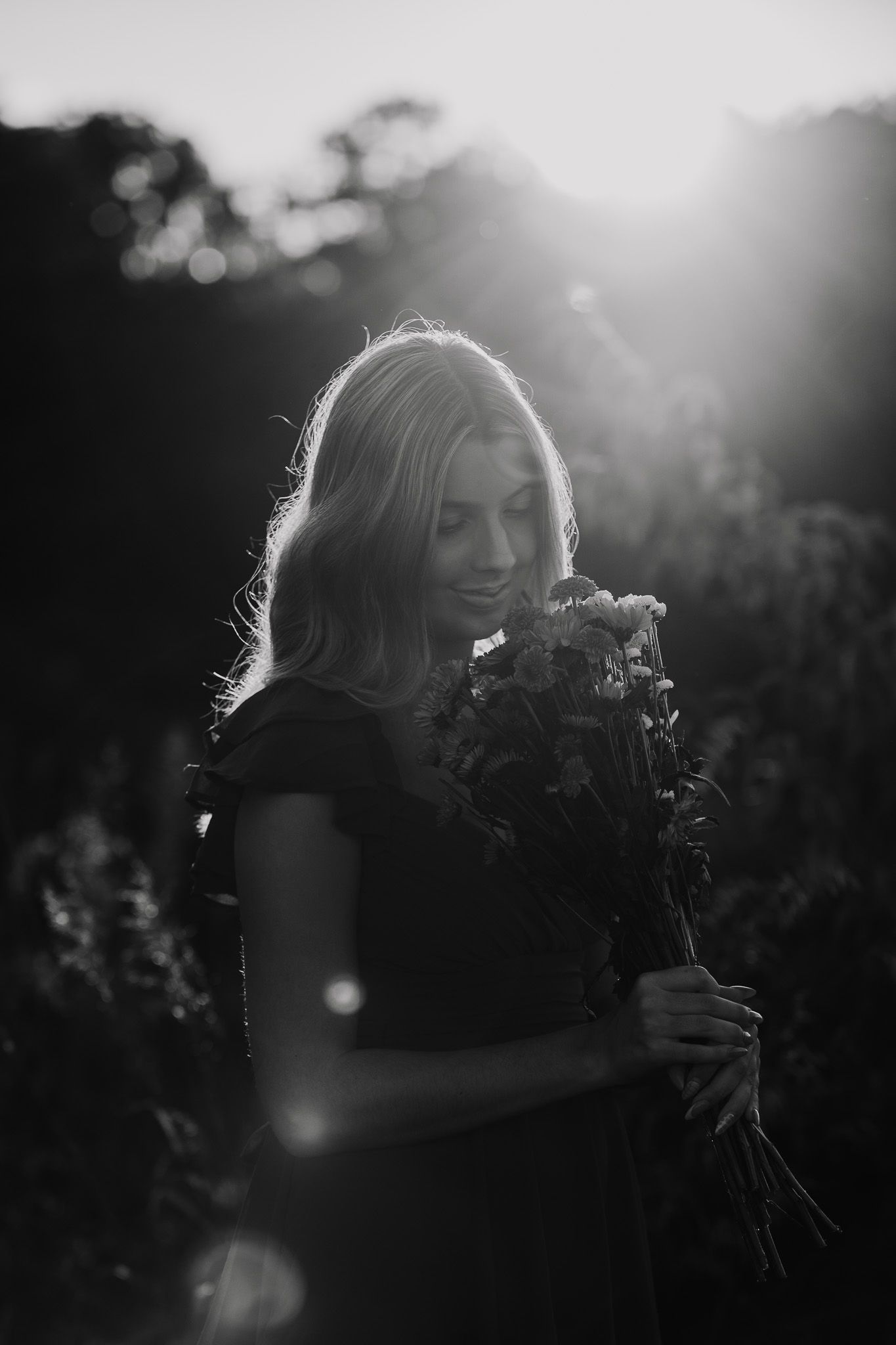 Silhouetted figure in backlit sunset scene with flowers.