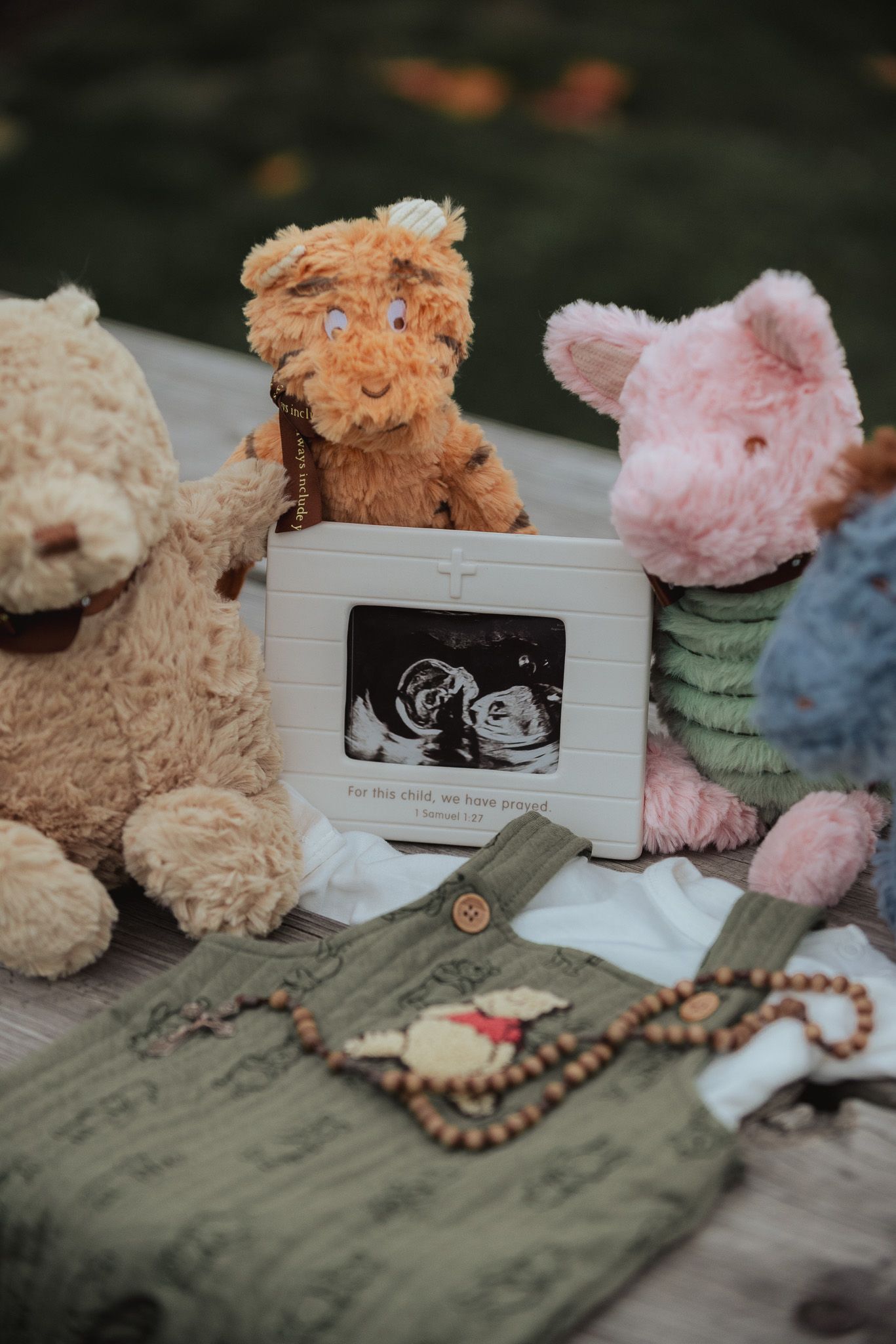 Stuffed animals and ultrasound photos arranged with beaded accessories on a textured surface.