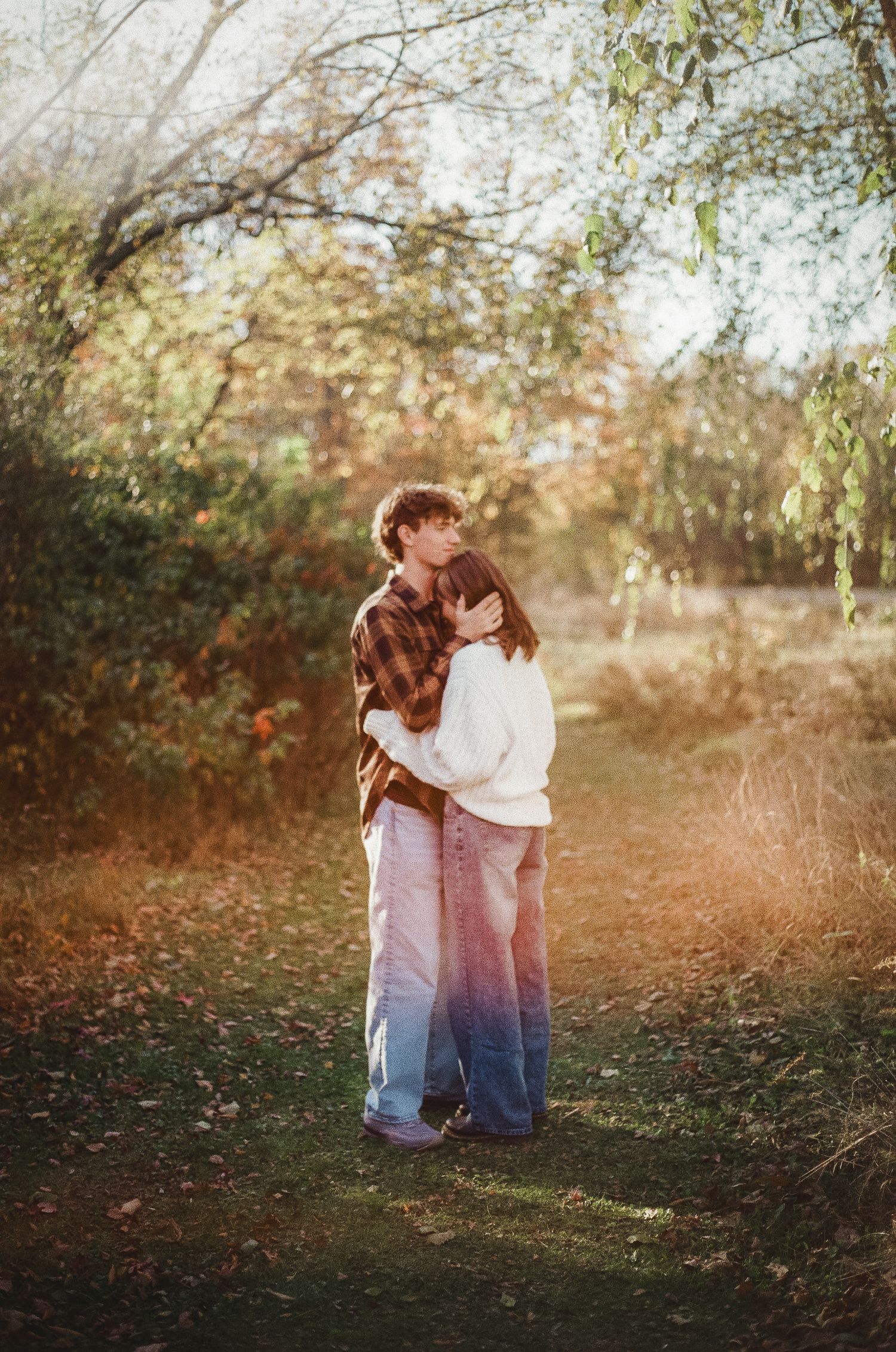 Two children embrace in a sunlit autumn garden setting with golden bokeh lighting effects in the background.