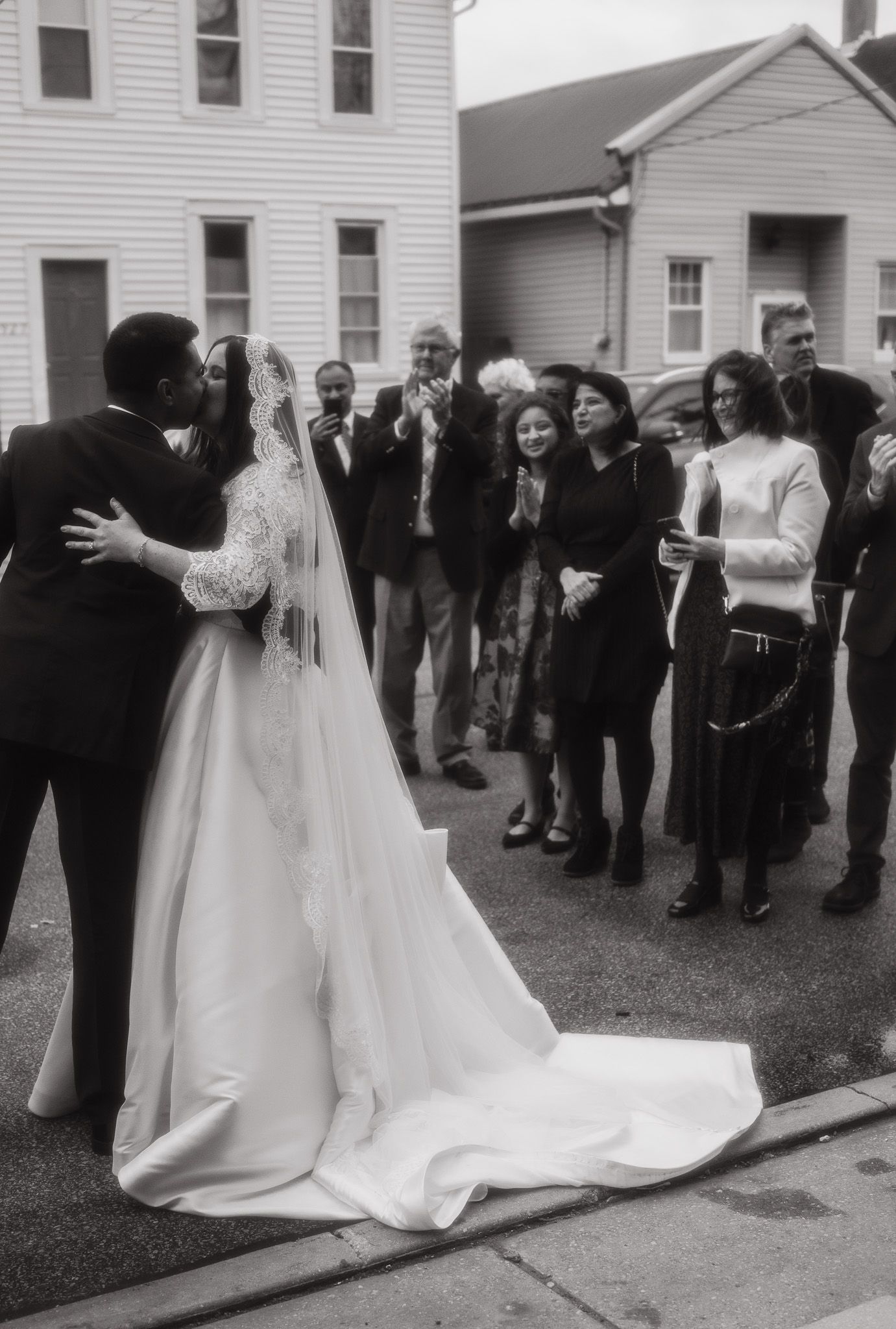A series of black and white wedding photos showing a couple and guests outside a white building in vintage style.
