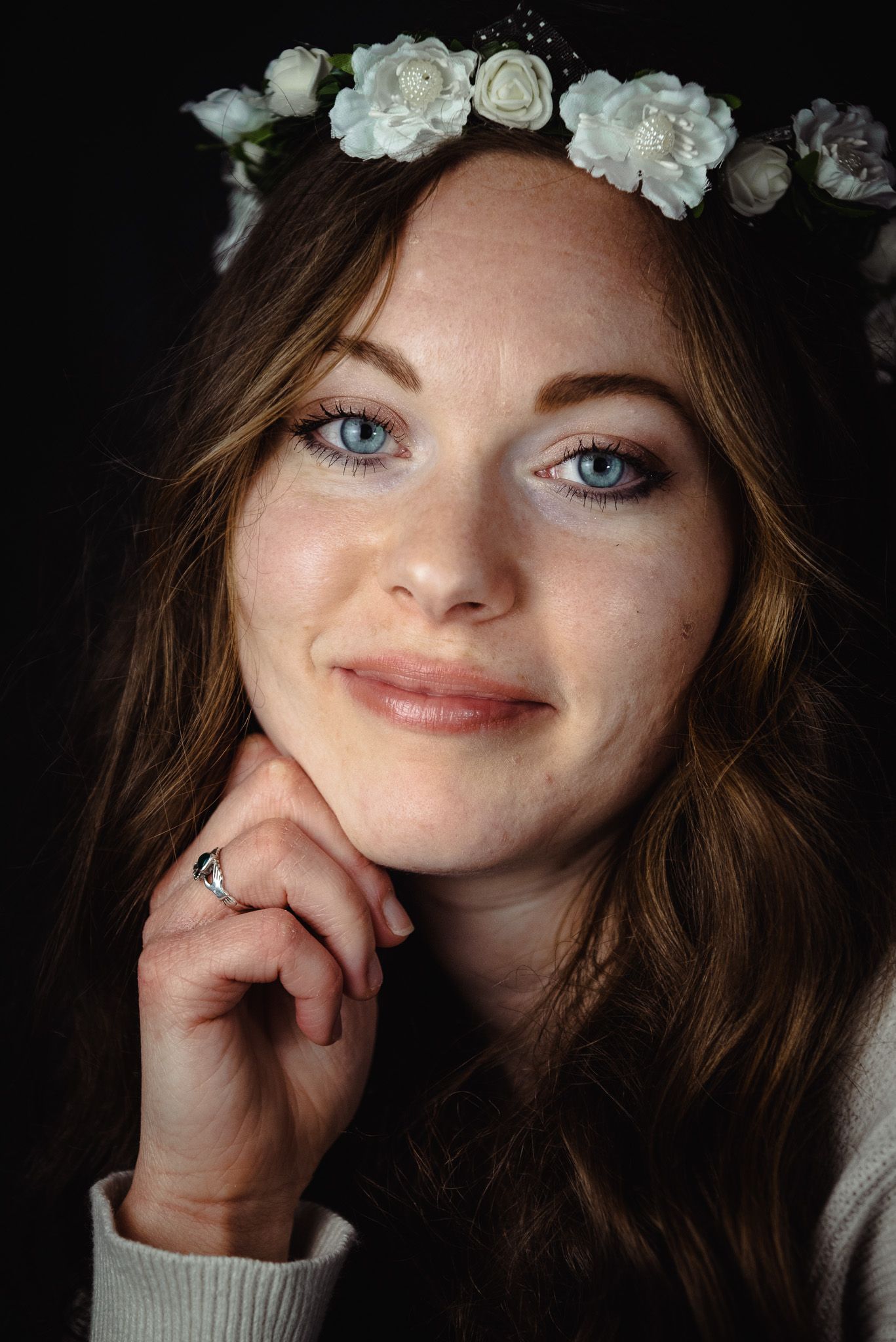 Ethereal portrait series featuring white floral crown and delicate lighting against dark backdrop.