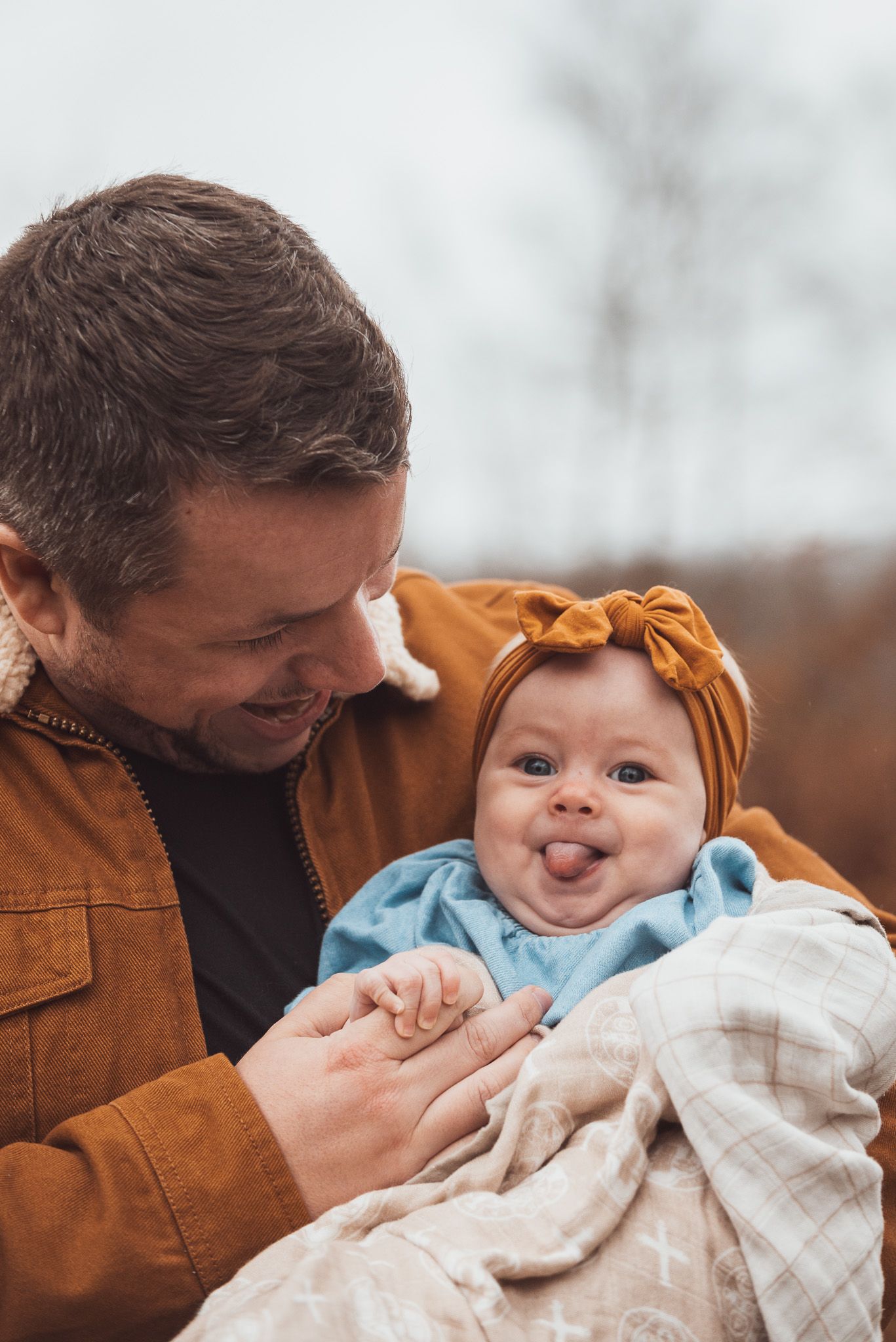 Joyful moments shared between parent and smiling baby bundled in a blanket outdoors.