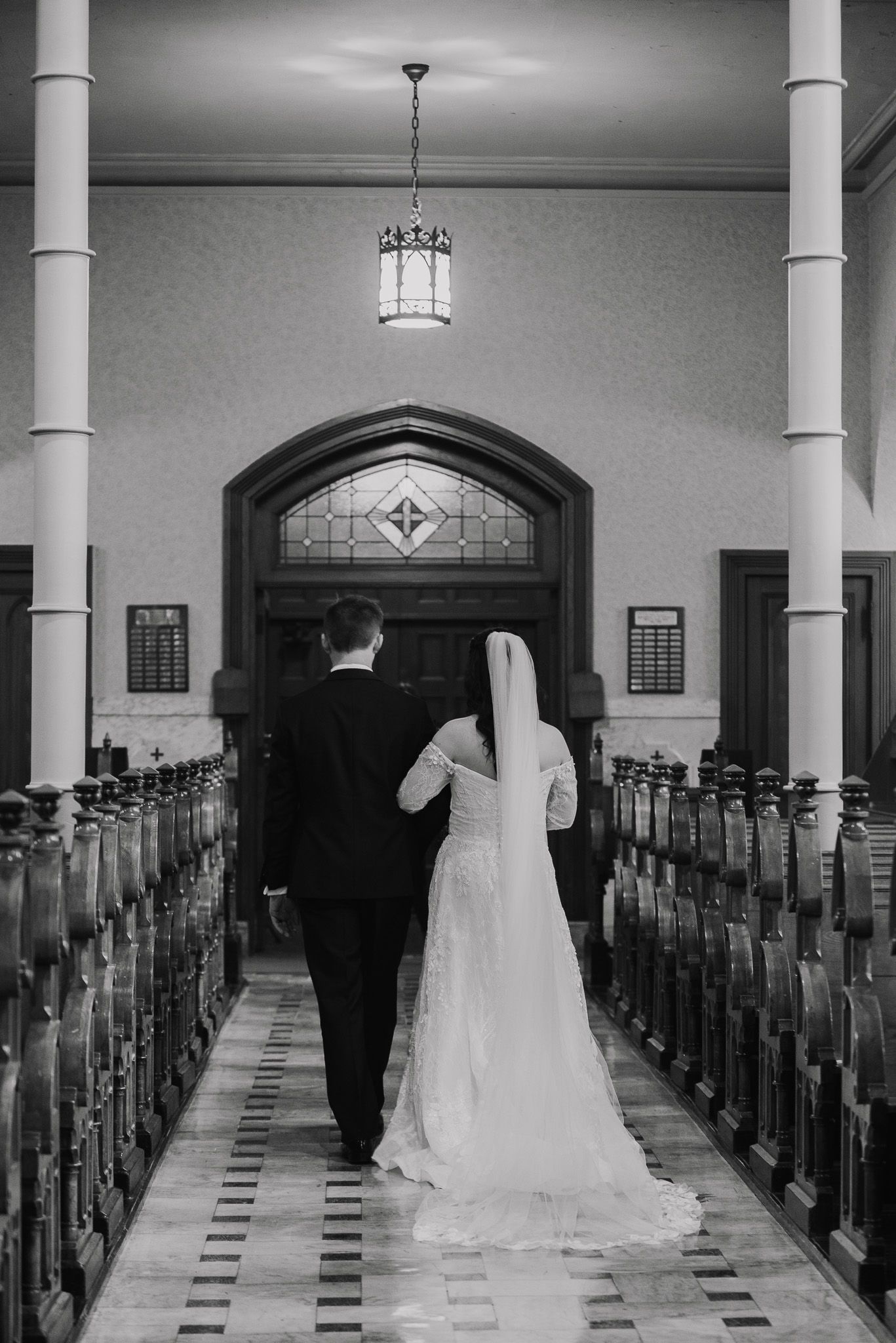 Black and white photo of a church interior with columns and pews during a wedding ceremony.