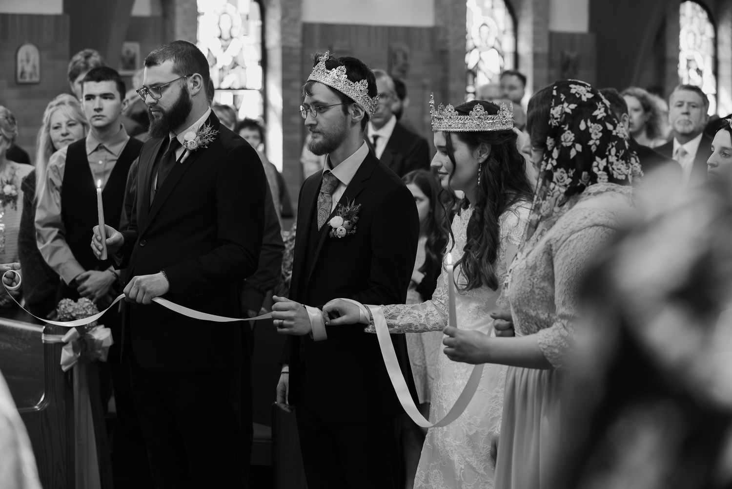 Wedding guests gather in formal attire for a group photo at an elegant indoor venue.