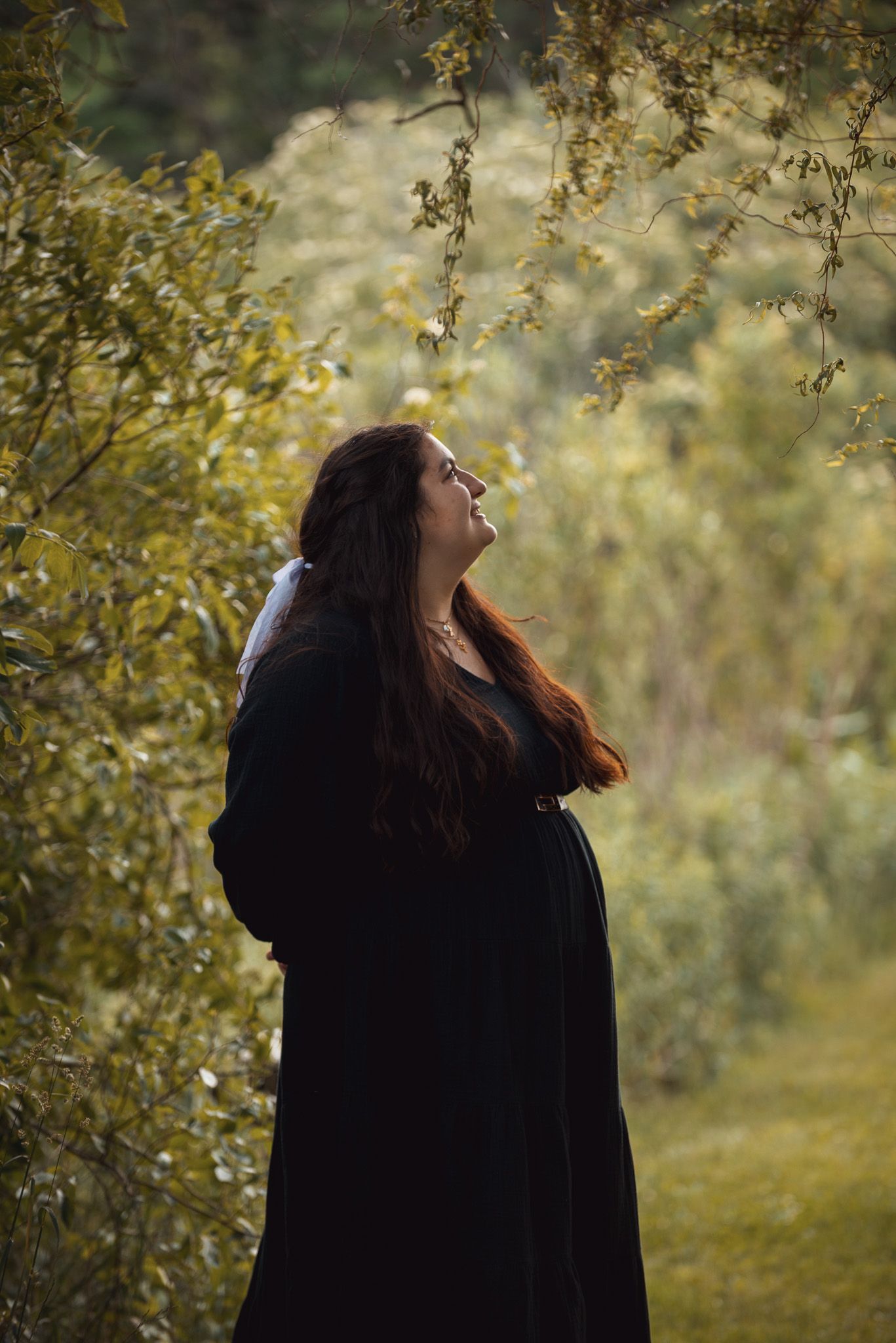 A dramatic silhouette in a flowing black dress against autumn foliage.