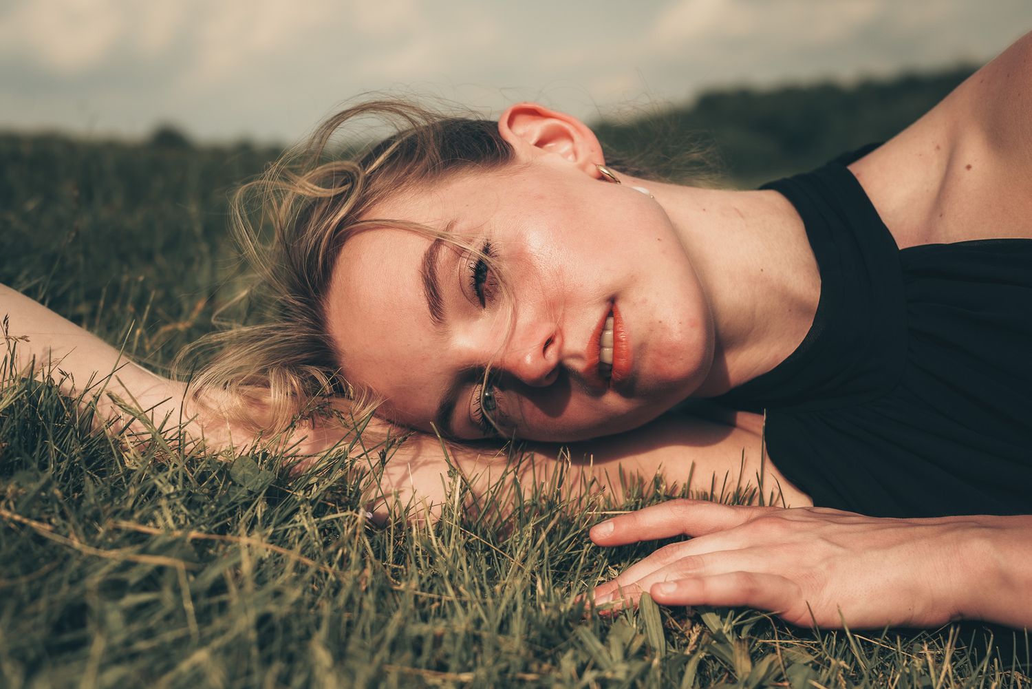 Outdoor portrait series showing relaxed poses in natural sunlit grass.