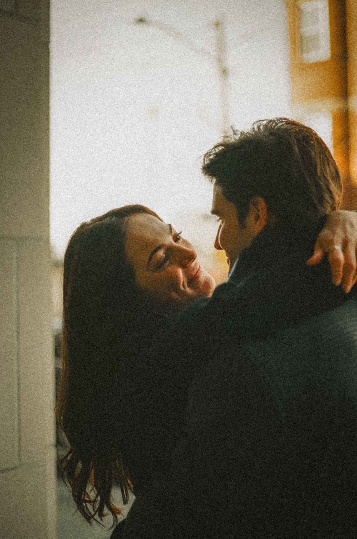 A romantic vintage-style film photograph shows an intimate couple embracing in warm lighting.