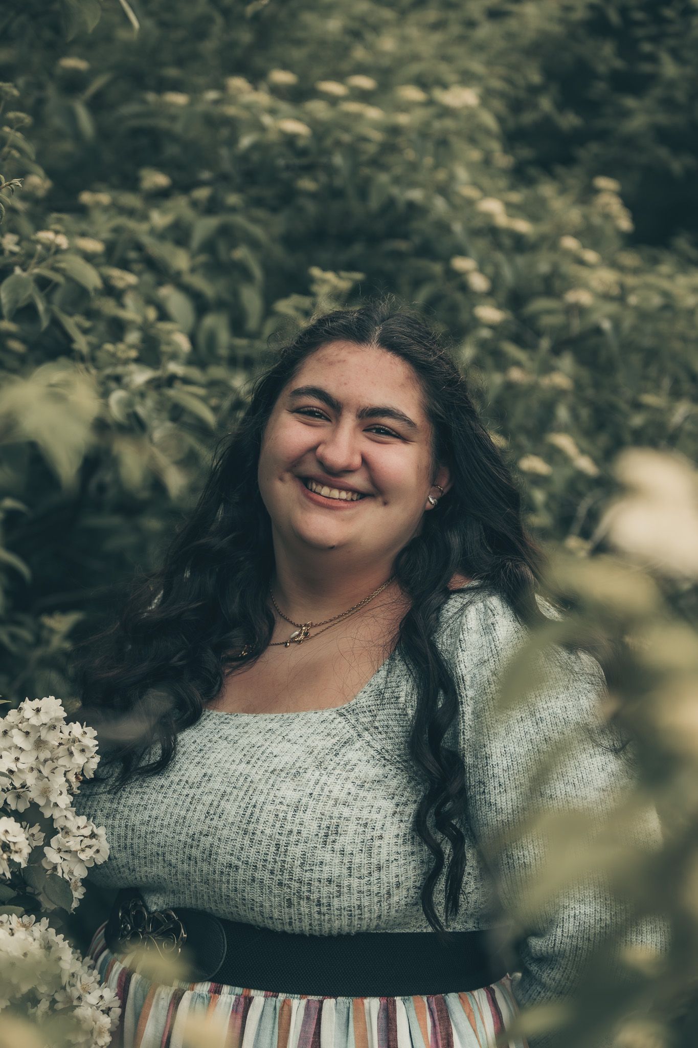 A joyful portrait in a garden setting wearing a vintage-inspired outfit.