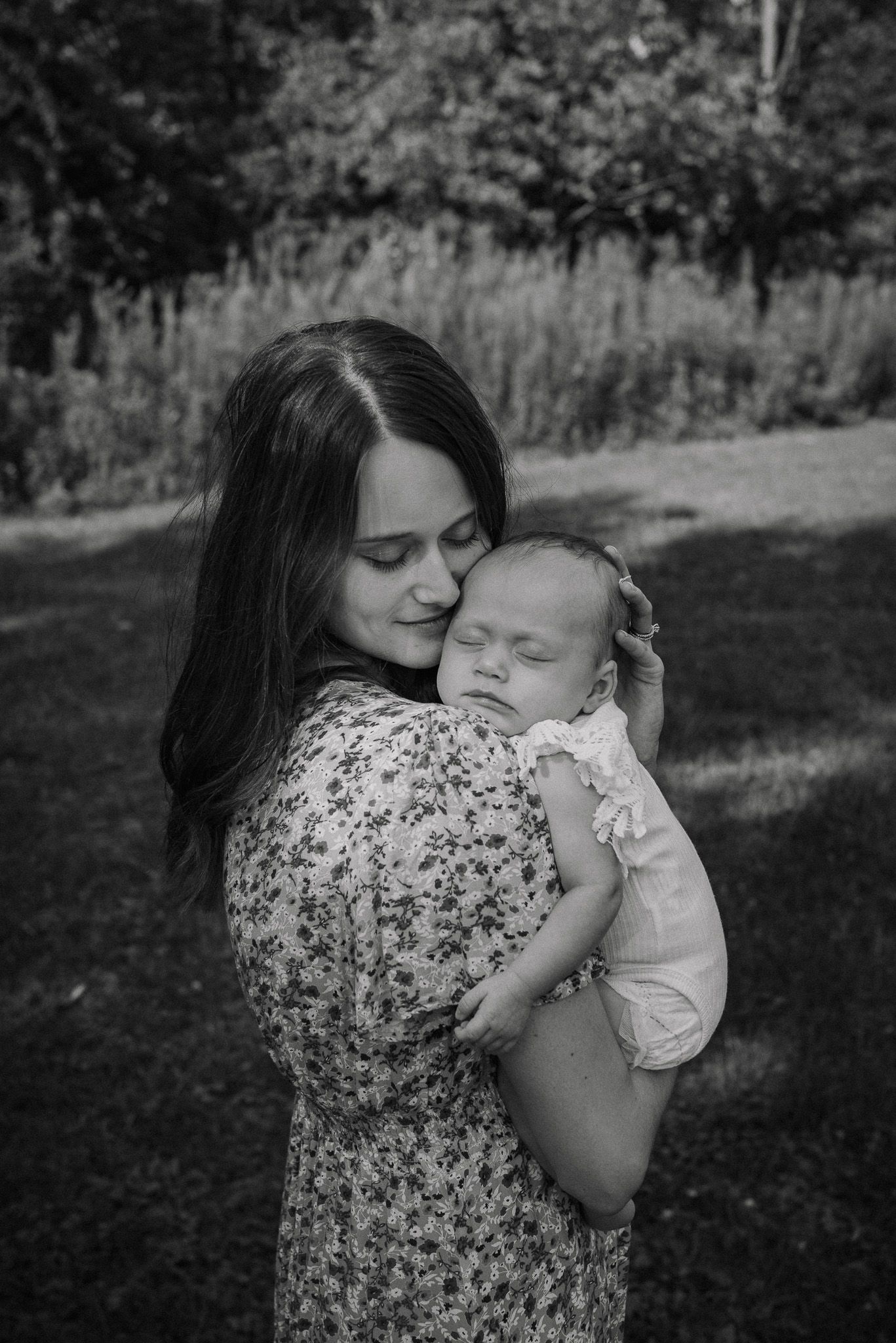 Tender moment between parent and baby outdoors in black and white photography.