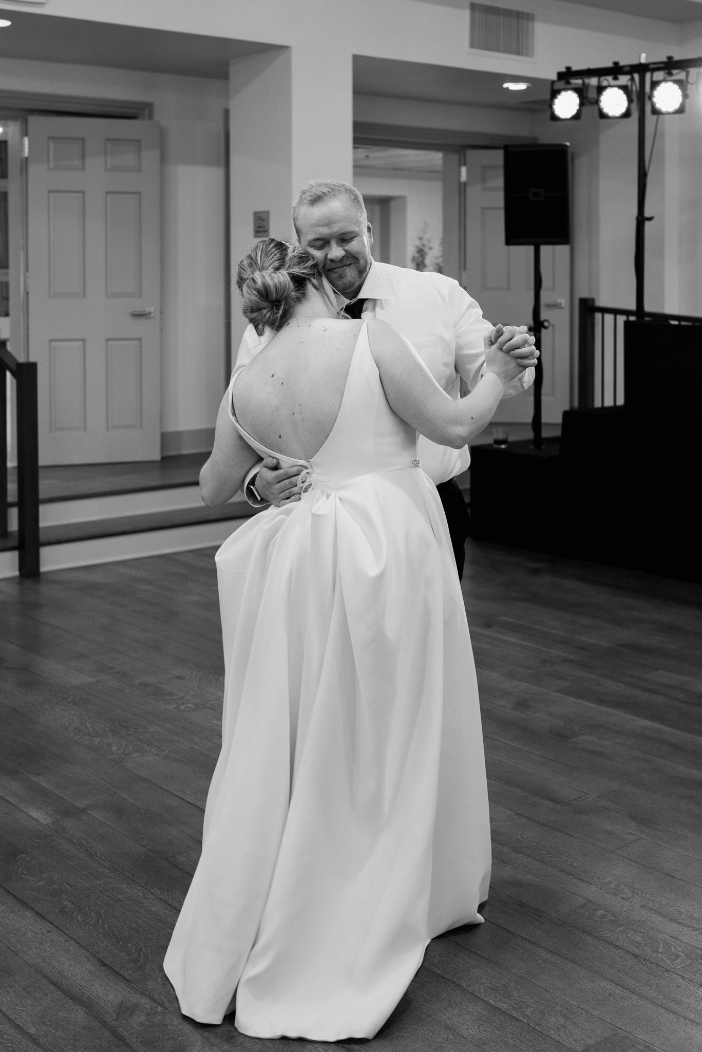 Couple shares their first dance on a polished wooden floor at their wedding reception.