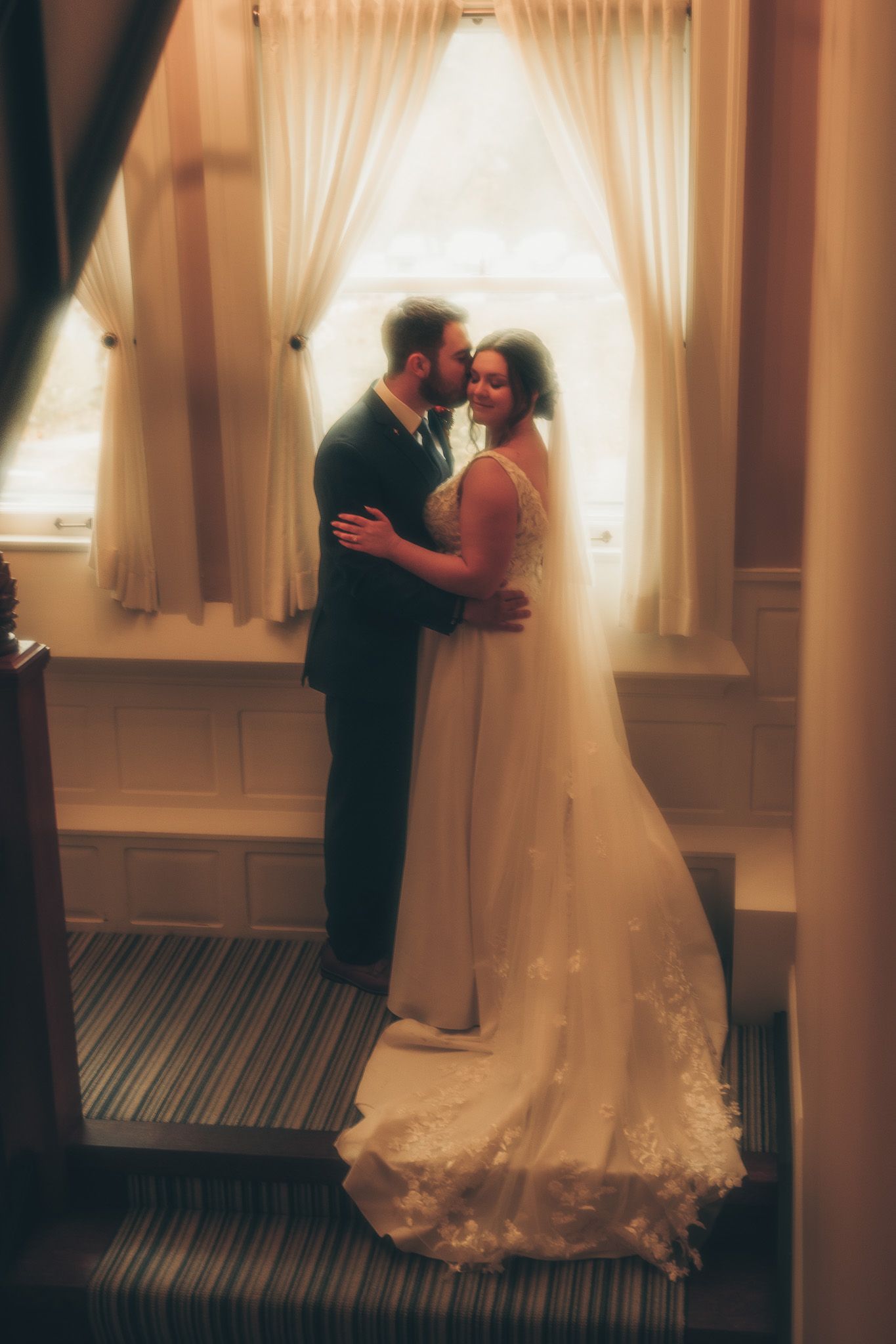 A romantic first look moment between newlyweds in a hotel room with soft window light and cream curtains.