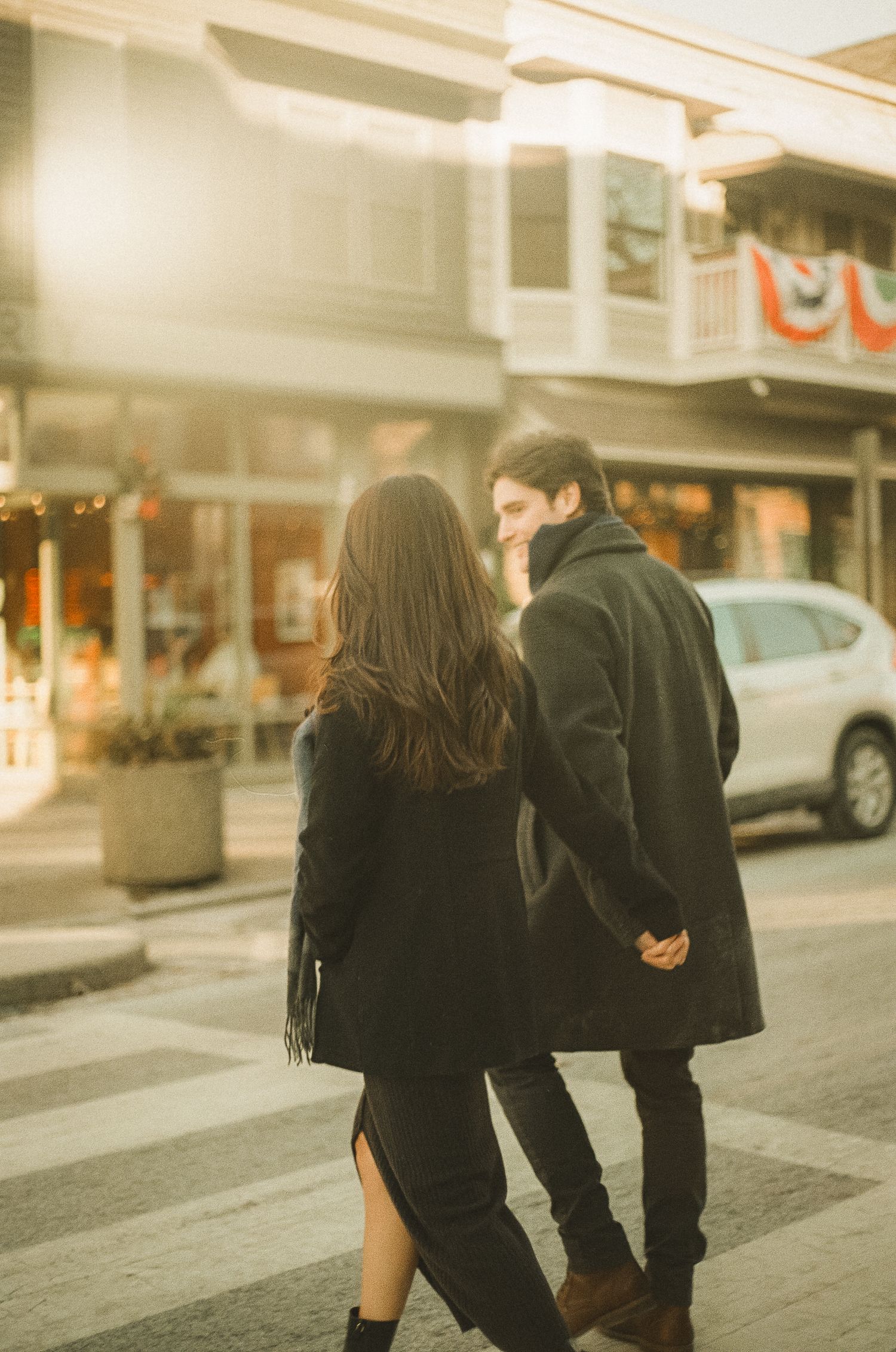 A couple in dark clothing walks across a crosswalk in a city street, shown in multiple sequential frames.