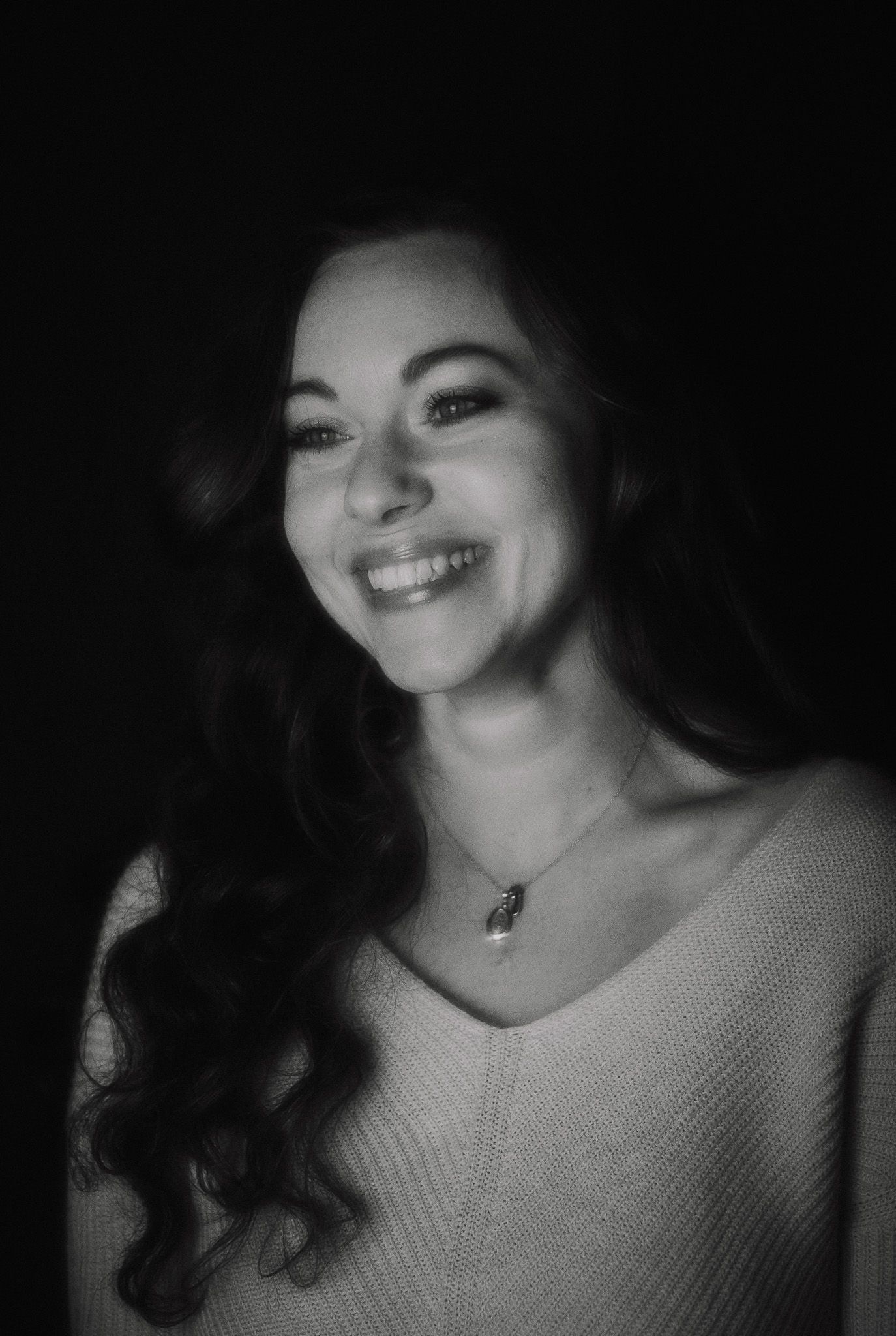 A series of black and white portraits showing joyful expressions and genuine smiles against a dark background.